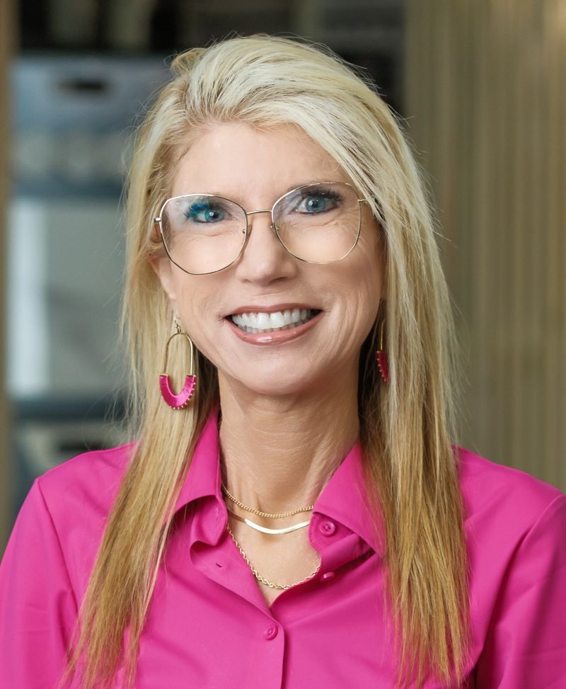 Woman with glasses smiles; black and white photo.