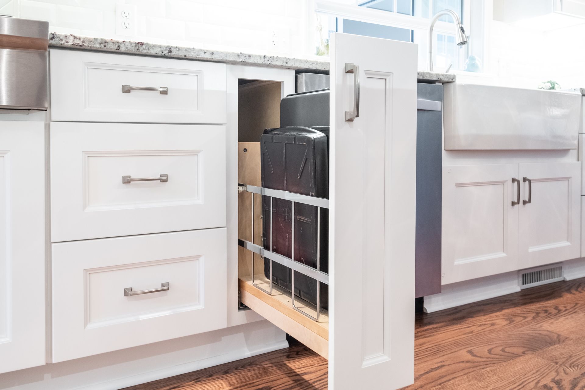 A kitchen with white cabinets and a pull out drawer.