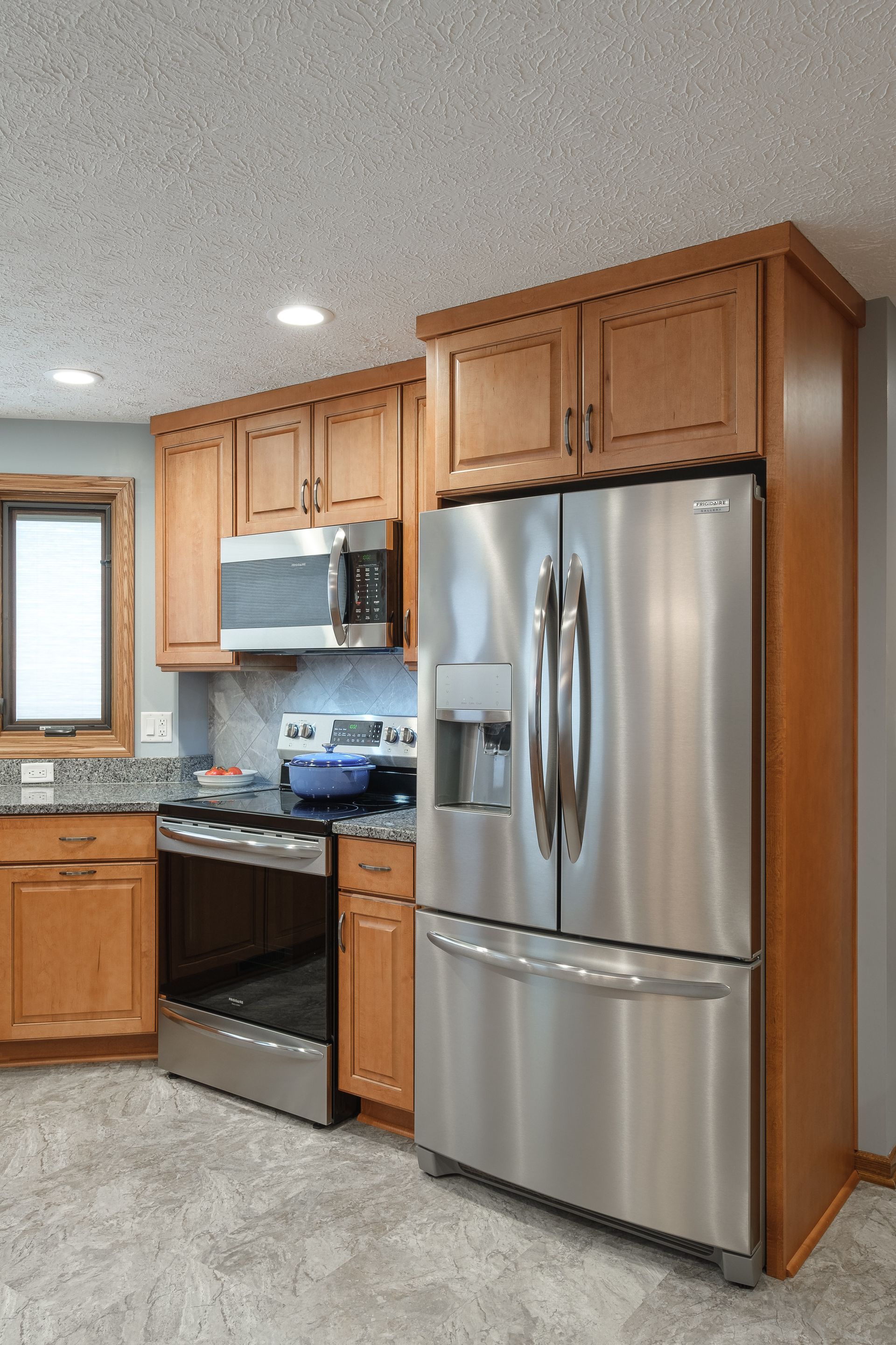 A kitchen with stainless steel appliances and wooden cabinets.