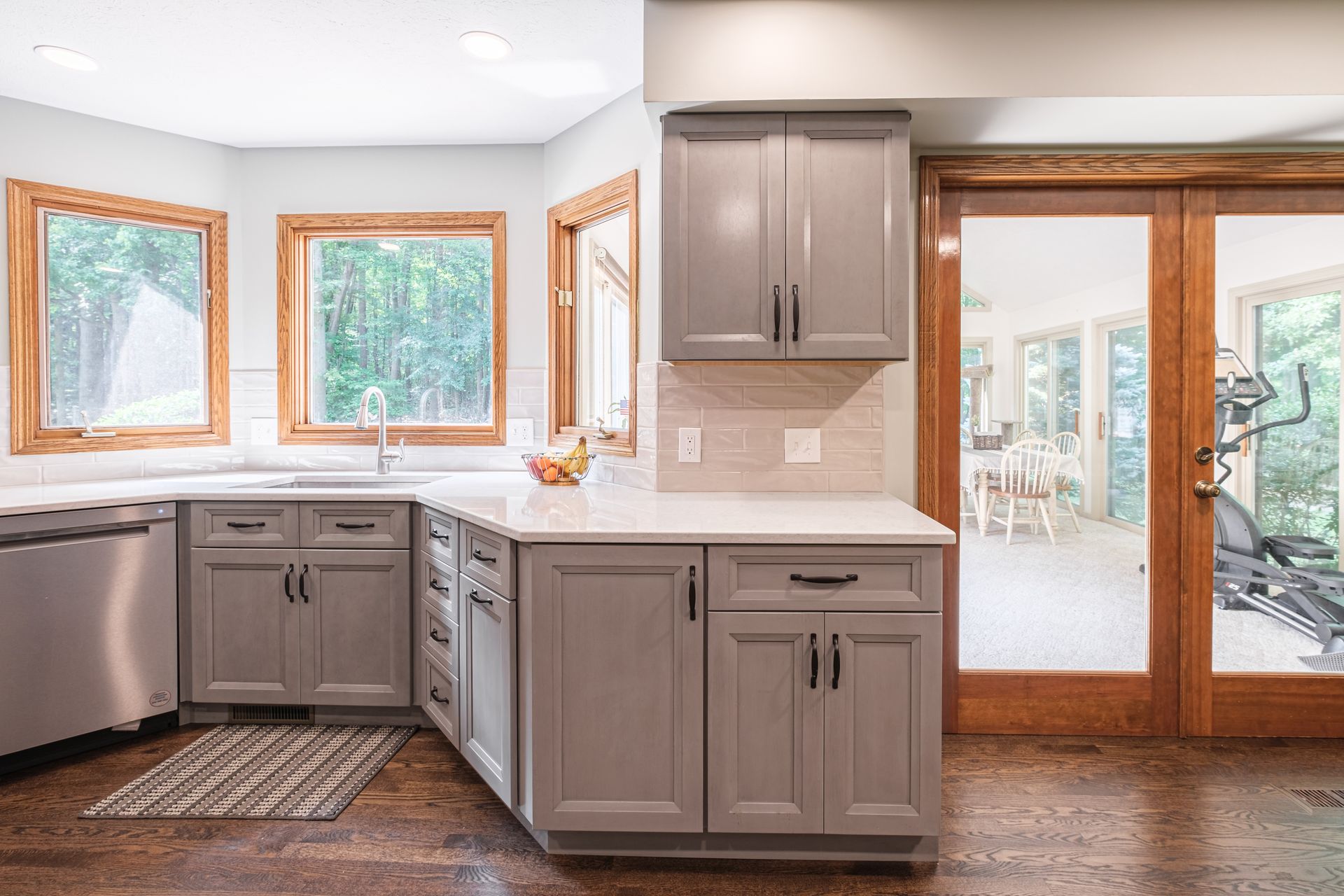 A kitchen with gray cabinets , stainless steel appliances , and hardwood floors.