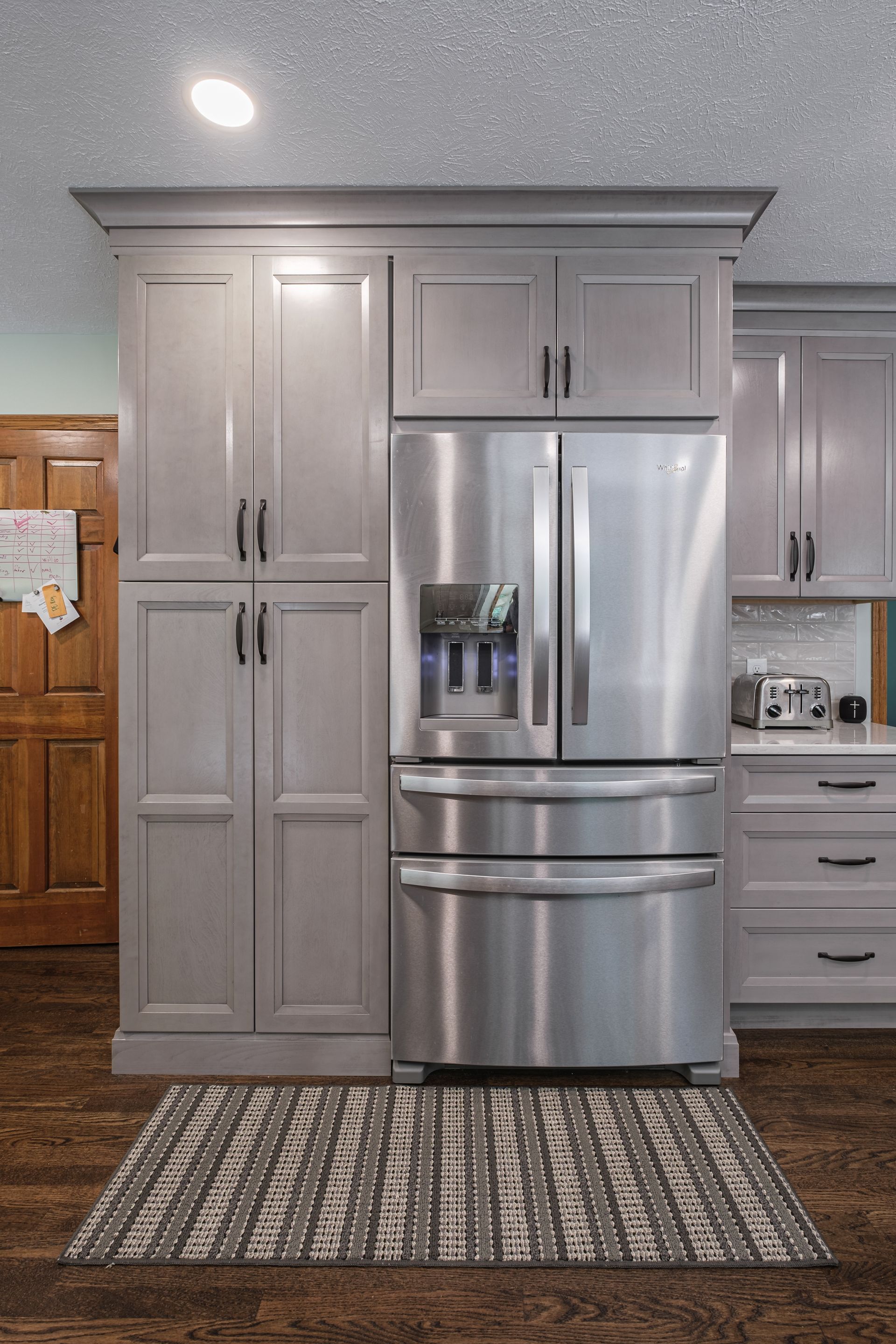 A kitchen with stainless steel appliances and gray cabinets.