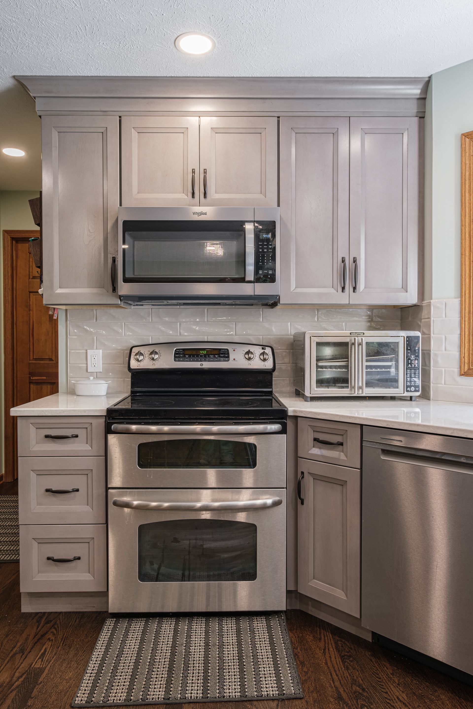 A kitchen with stainless steel appliances and gray cabinets.