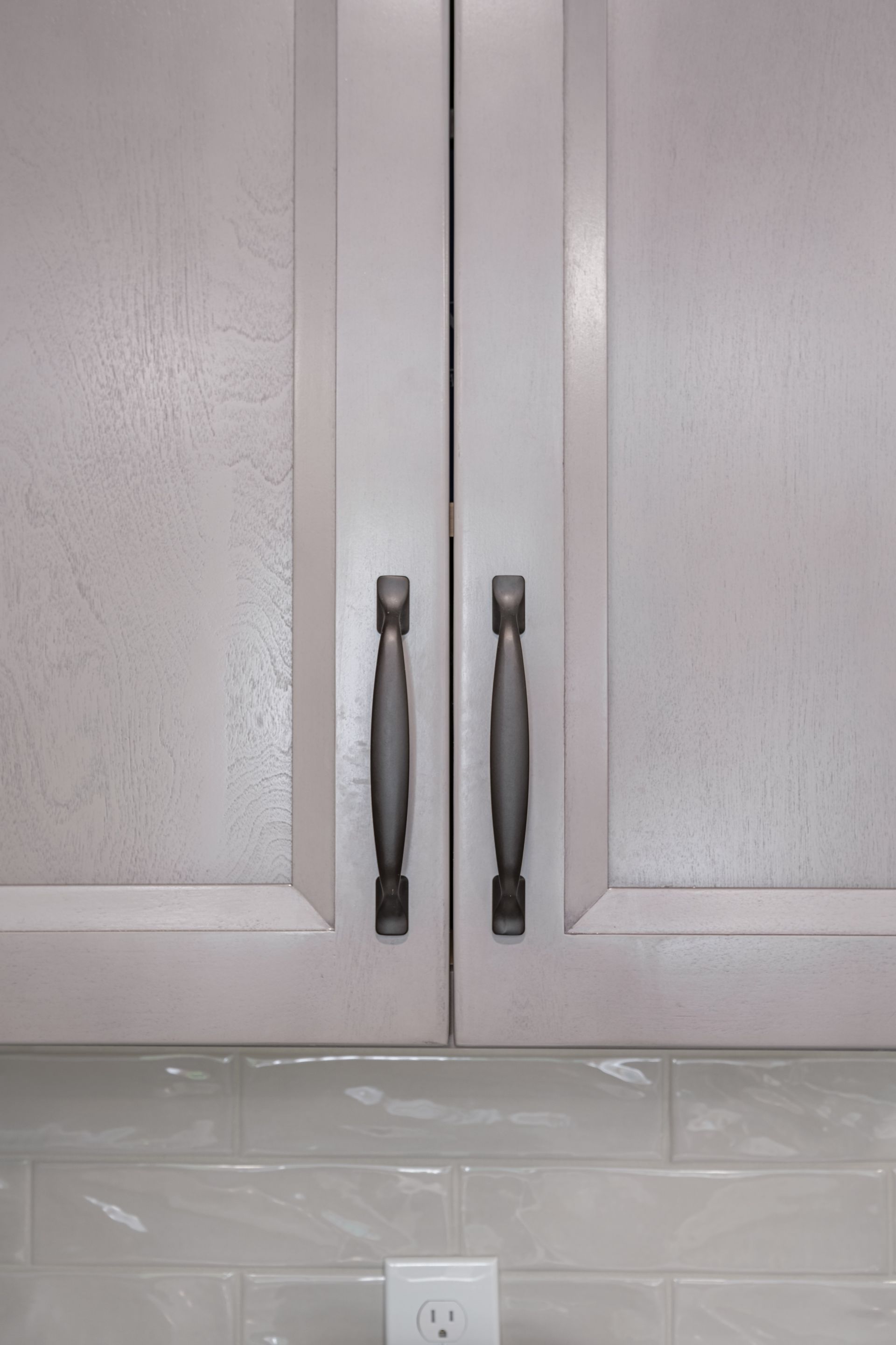 A close up of a kitchen cabinet with black handles.