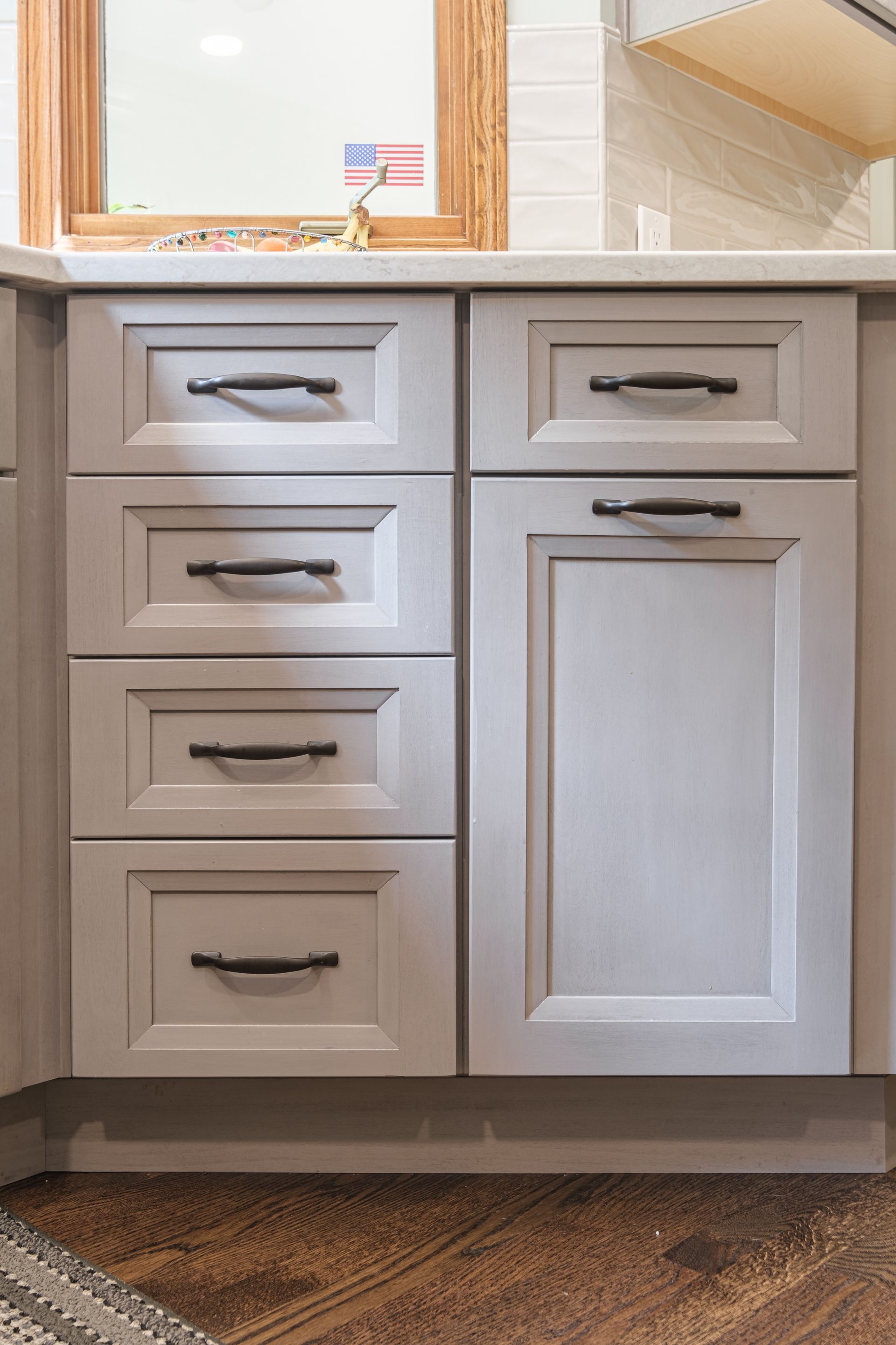 A kitchen with white cabinets and black handles and a sink.