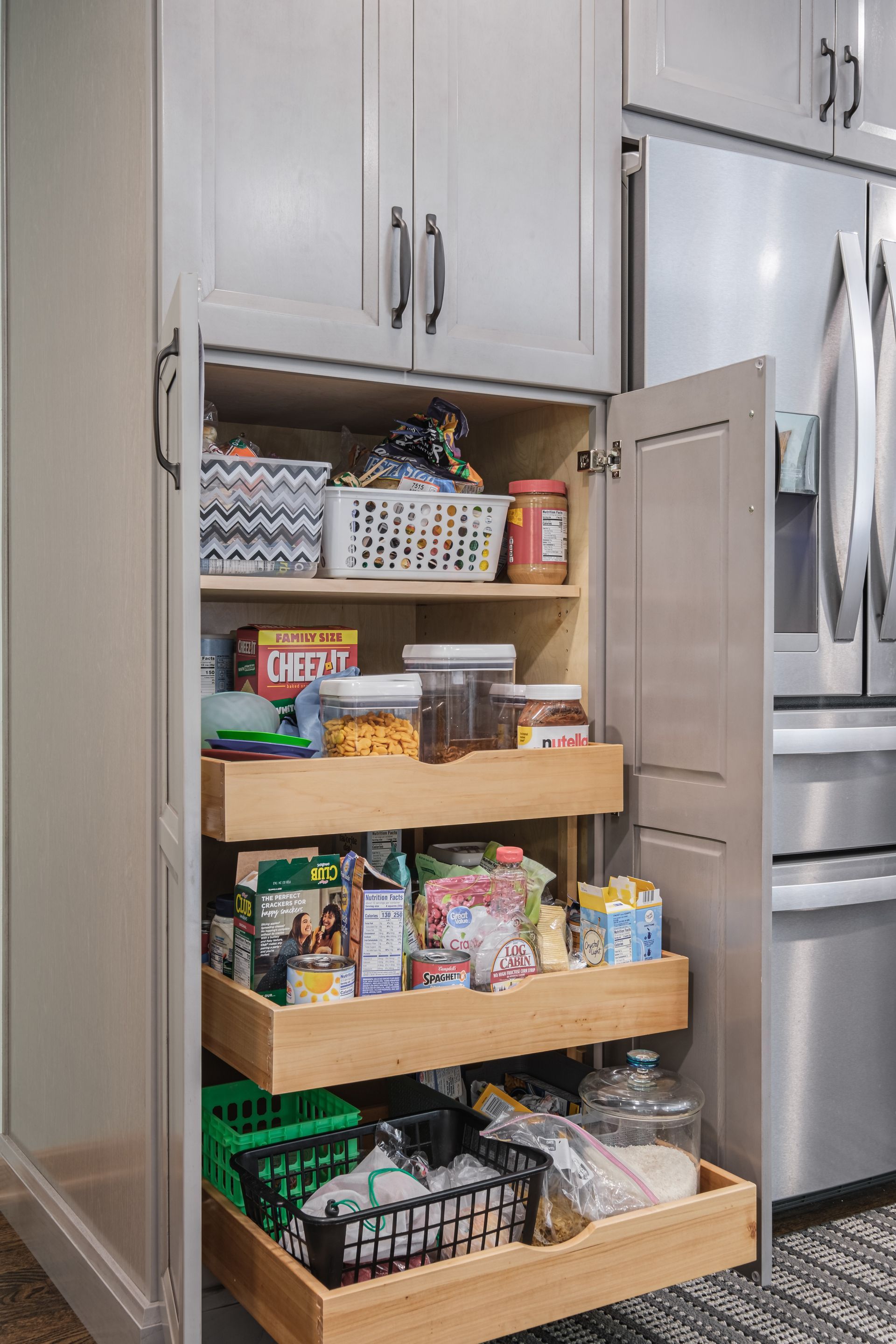 A kitchen pantry with drawers pulled out of it filled with food.