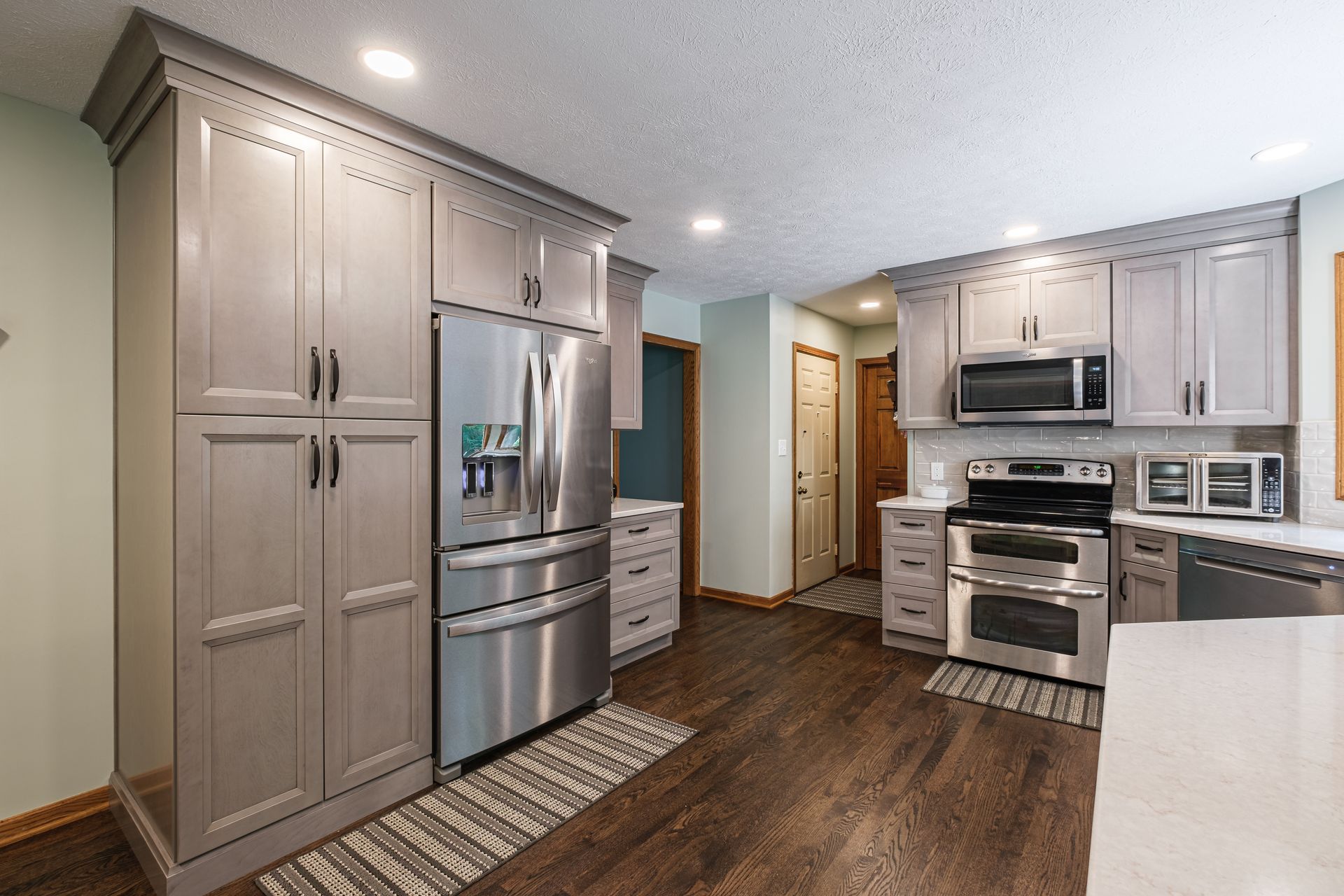 A kitchen with stainless steel appliances and gray cabinets.