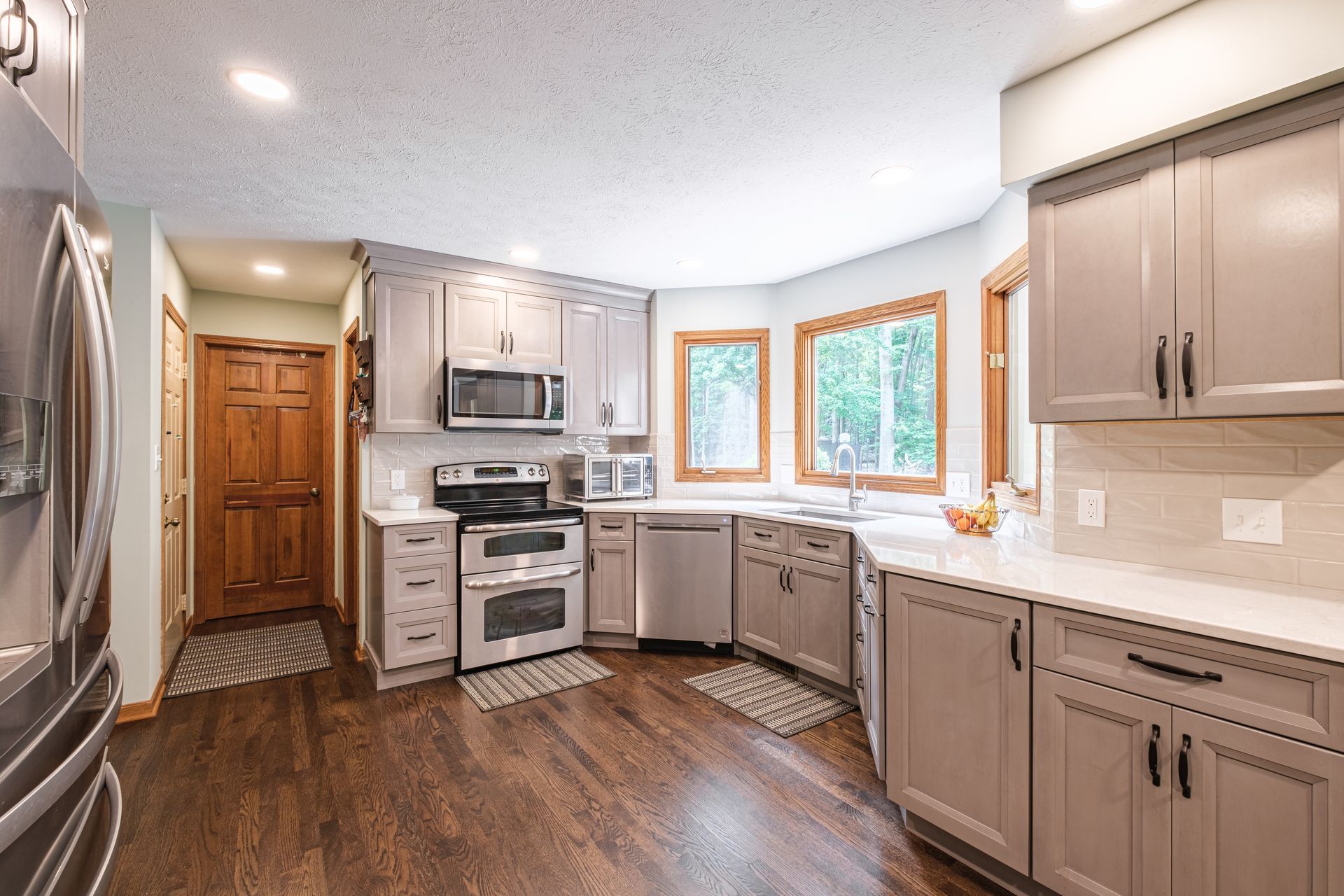 A kitchen with gray cabinets , stainless steel appliances , and hardwood floors.