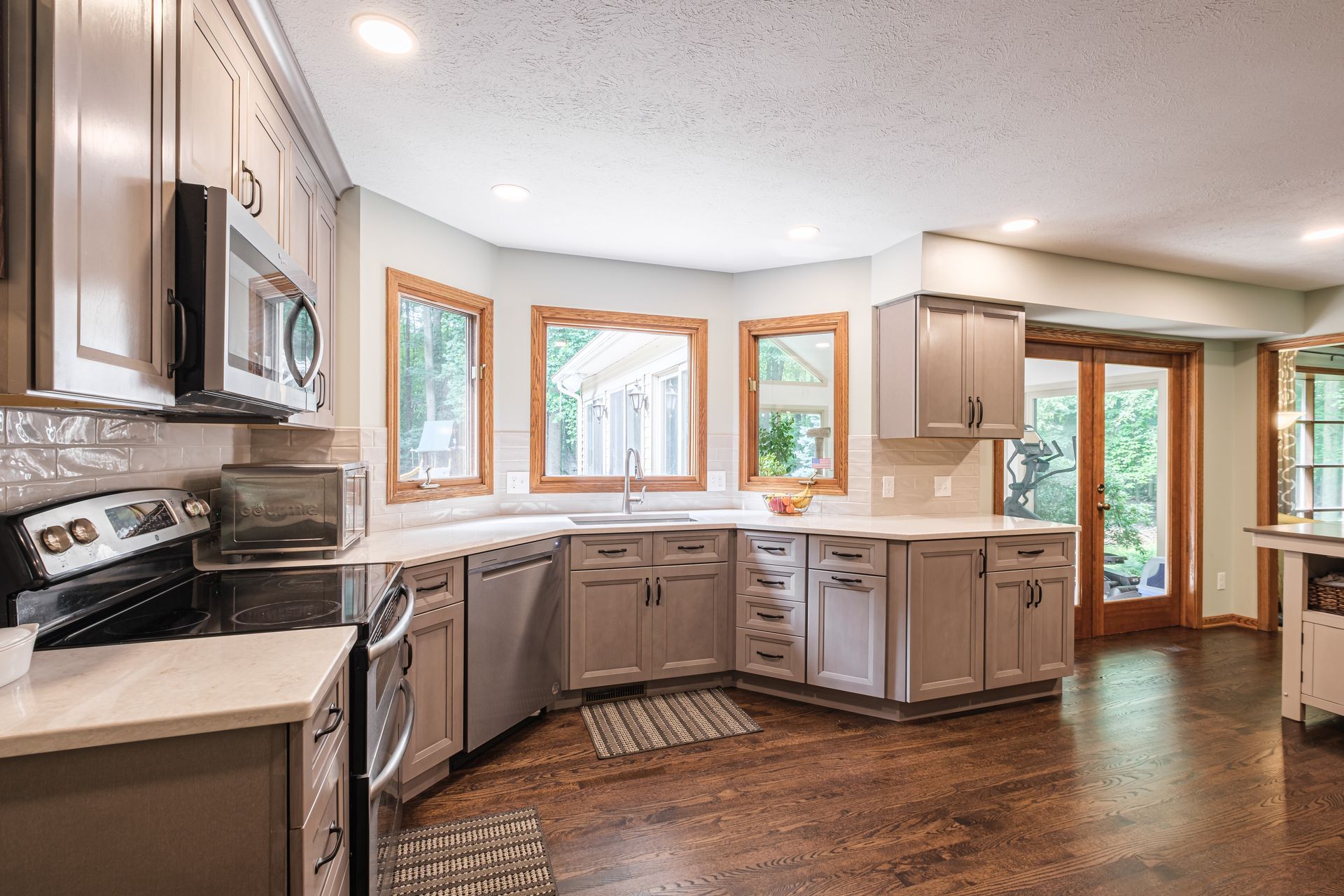 A kitchen with stainless steel appliances , gray cabinets , and hardwood floors.