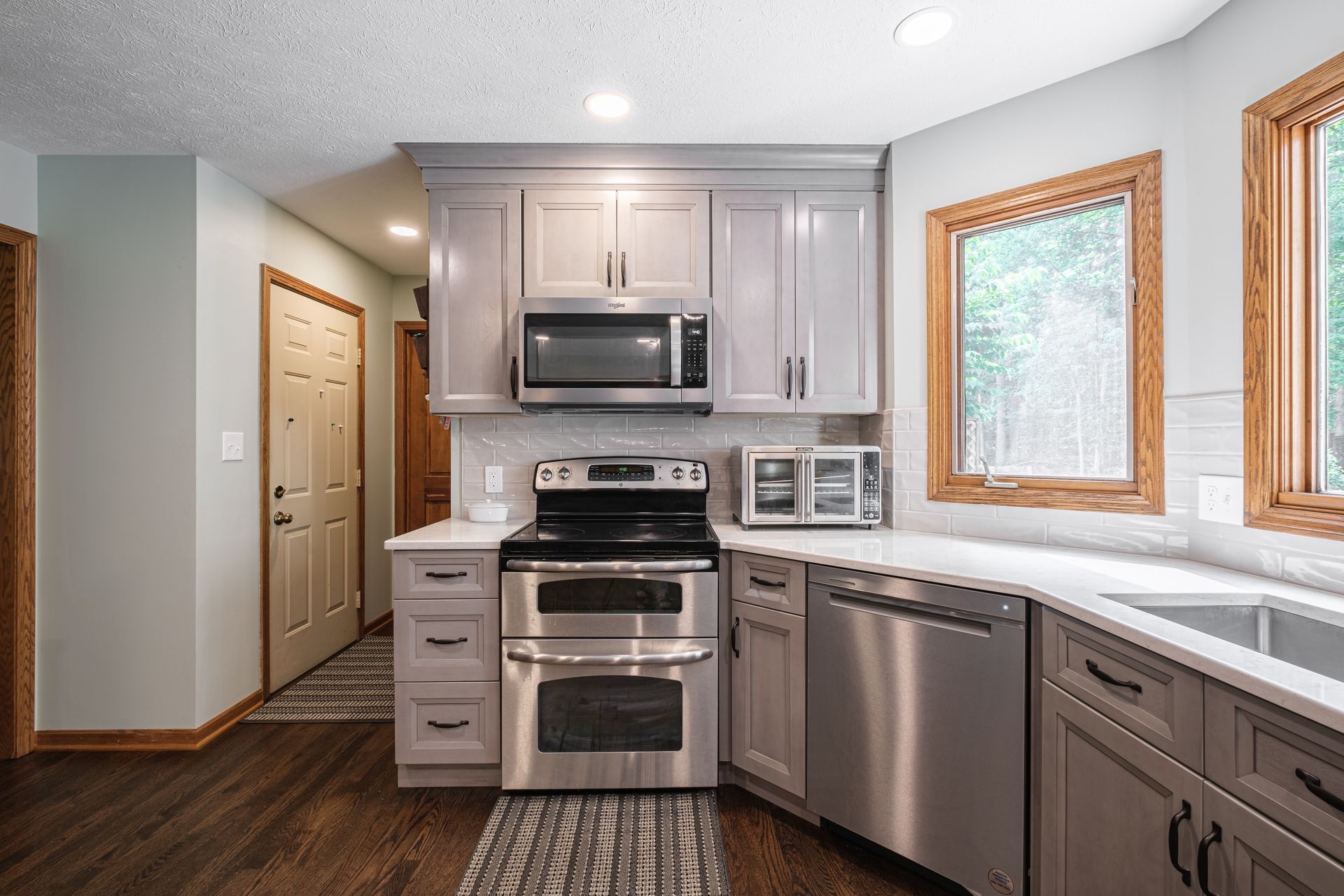 A kitchen with stainless steel appliances and gray cabinets.