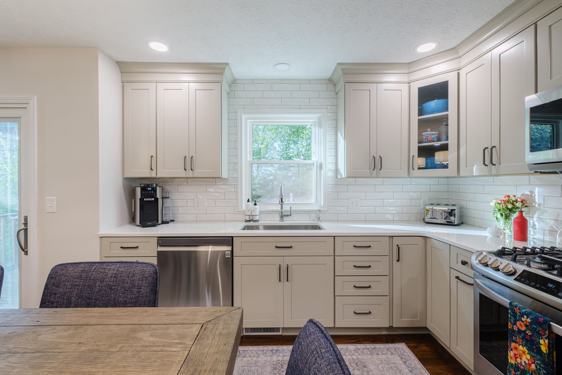 A kitchen with white cabinets , stainless steel appliances , a table and chairs.