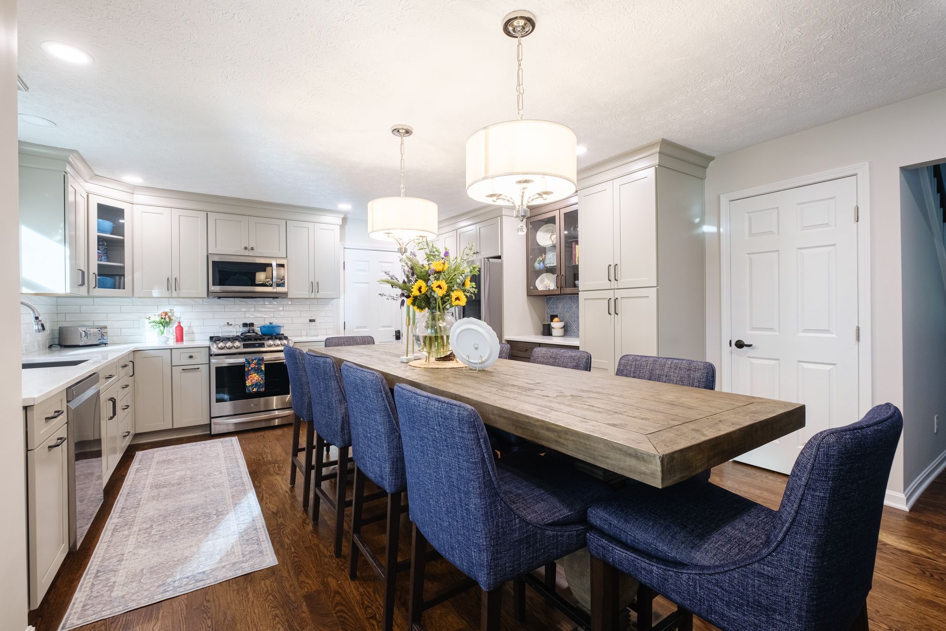 A kitchen with a long wooden table and blue chairs.