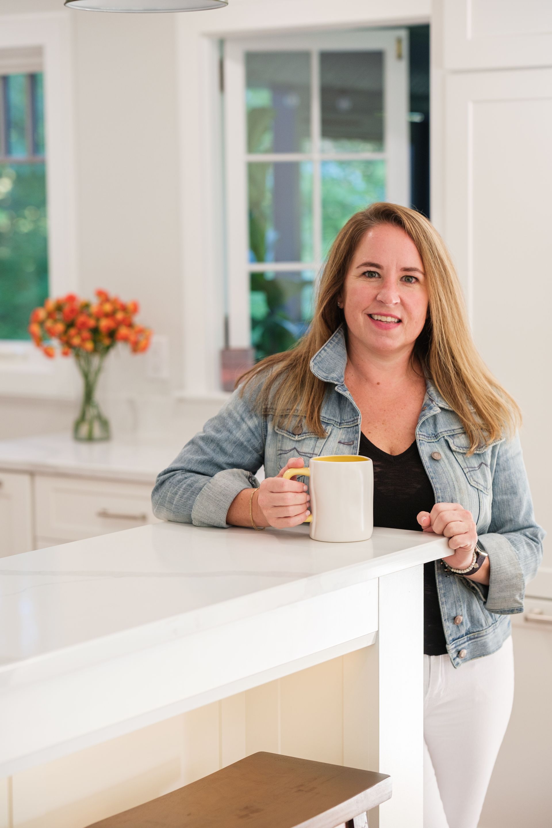 A woman is standing in a kitchen holding a cup of coffee.