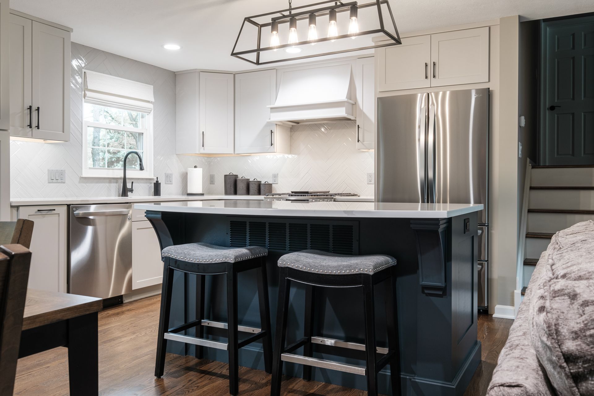 A kitchen with stainless steel appliances and a large island with stools.