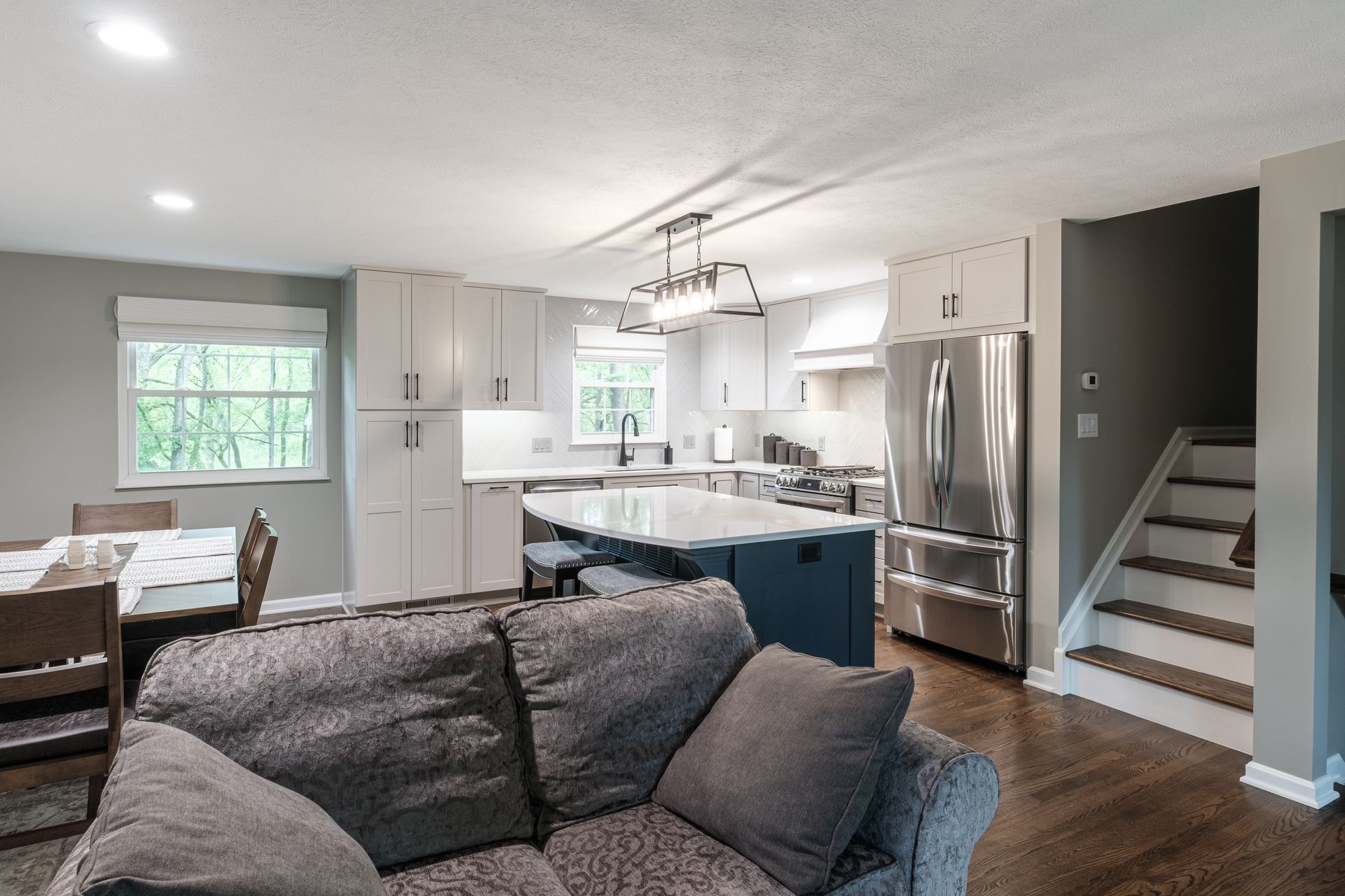 A living room with a couch and stairs leading to a kitchen.
