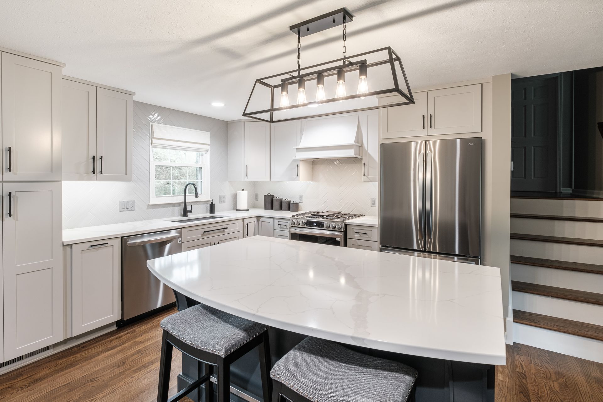 A kitchen with white cabinets , stainless steel appliances , and a large island.