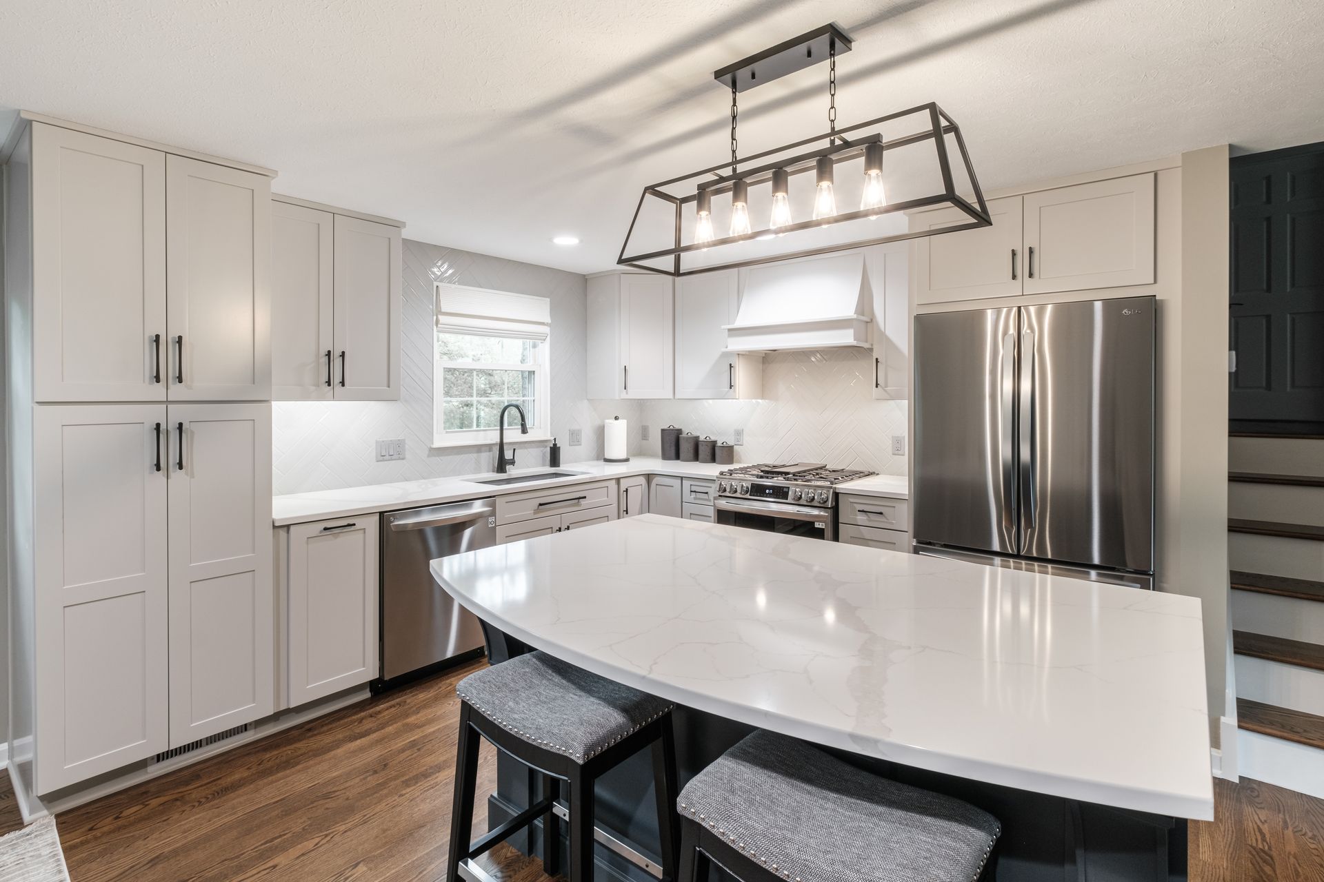 A kitchen with white cabinets , stainless steel appliances , and a large island.