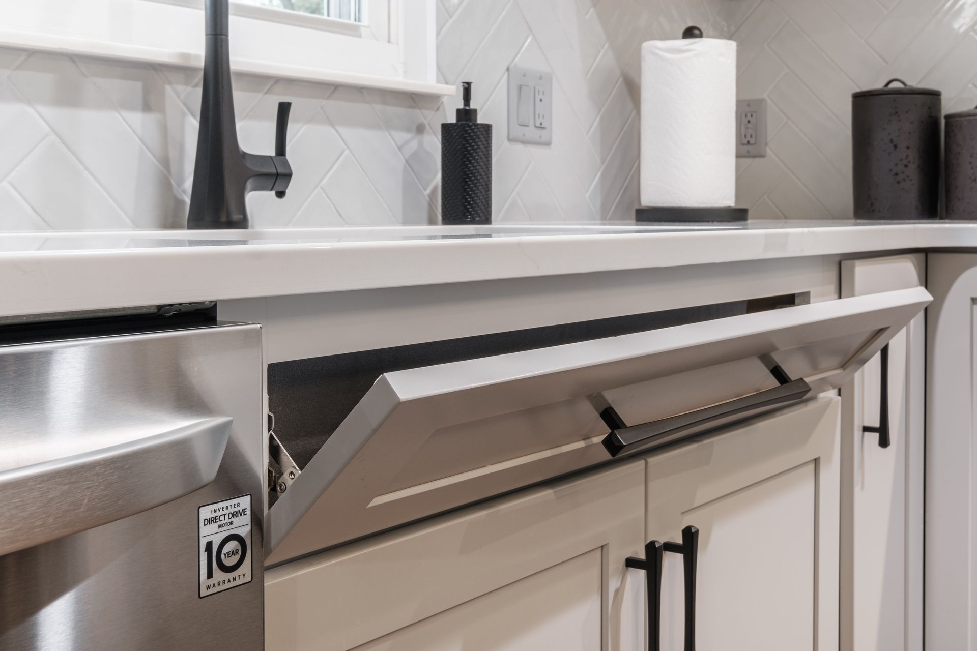 A kitchen with white cabinets and a stainless steel dishwasher with the door open.