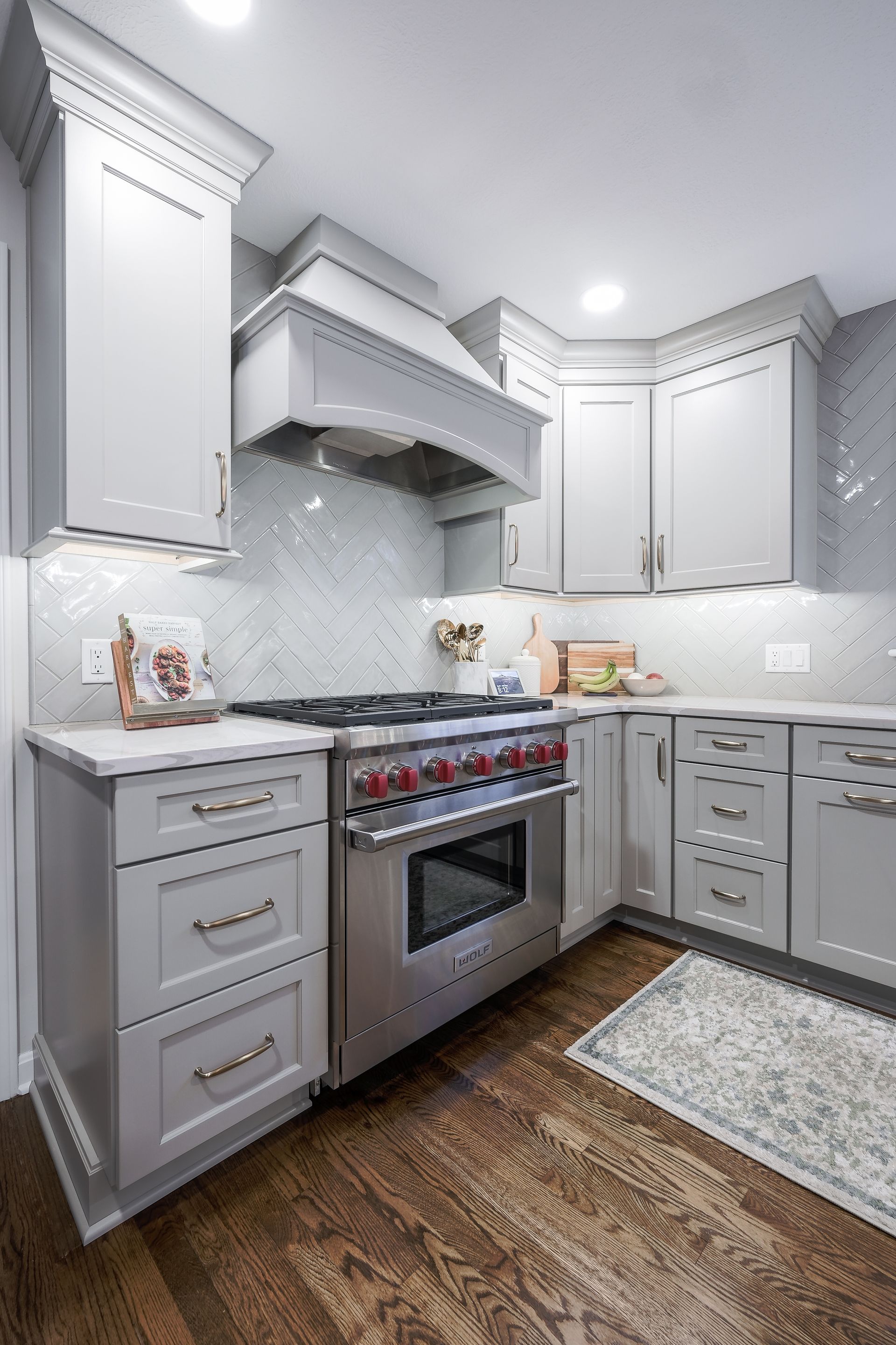 Gray kitchen with stainless steel oven, cabinets, and dark wood floor.