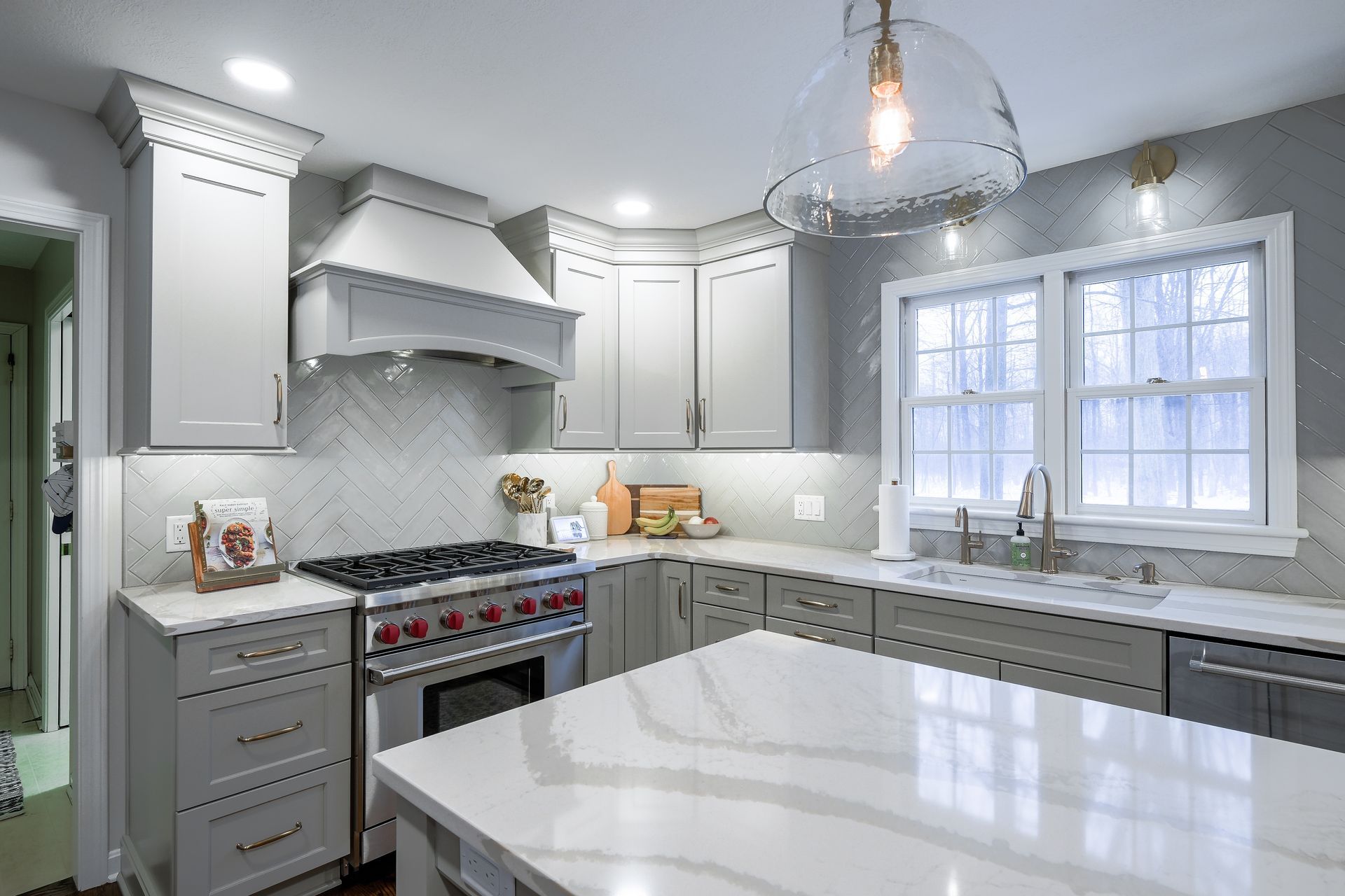 Modern gray kitchen with stainless steel appliances, white countertops, and a large island.