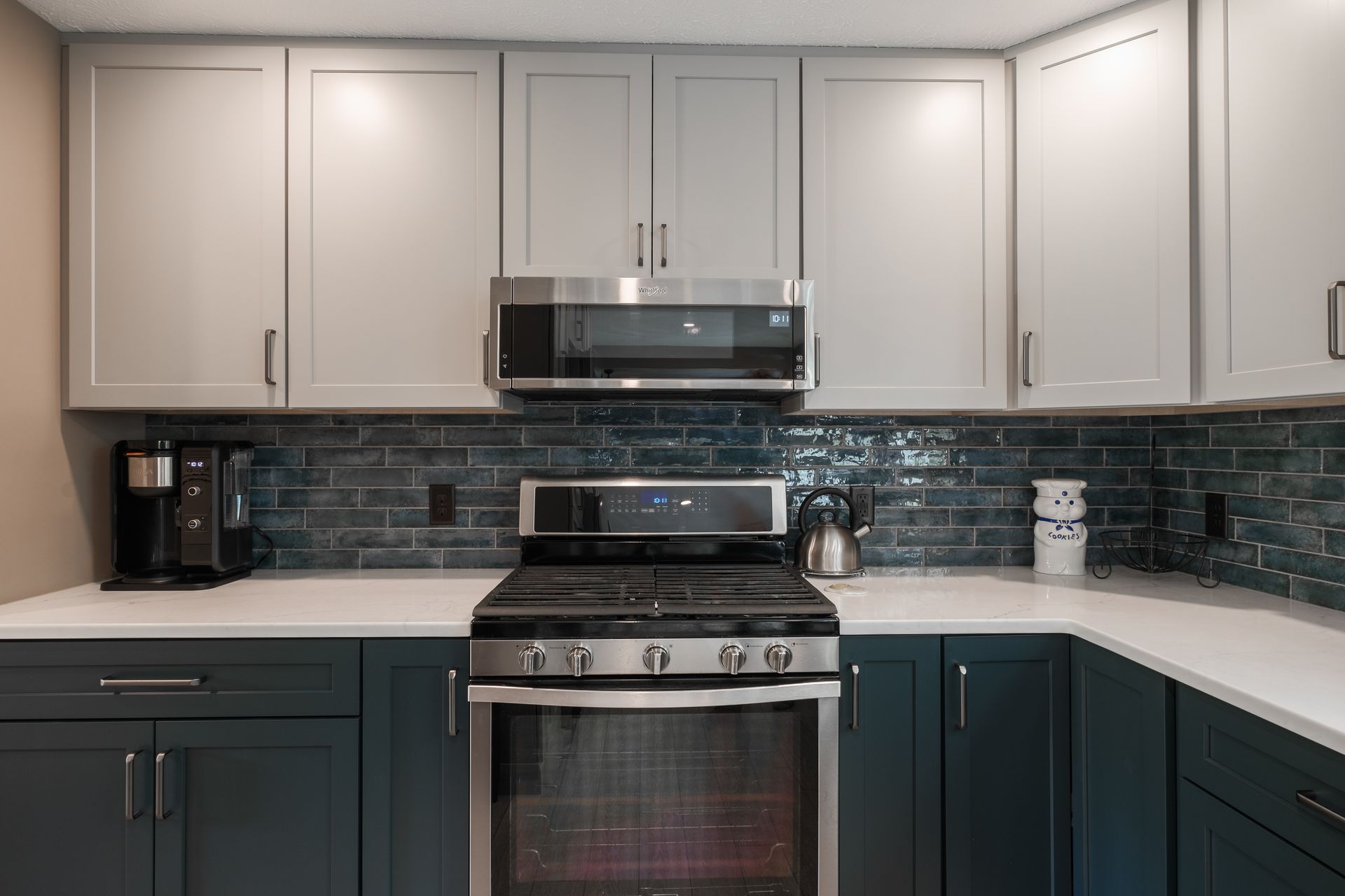 A kitchen with blue cabinets , a stove , a microwave , and a coffee maker.