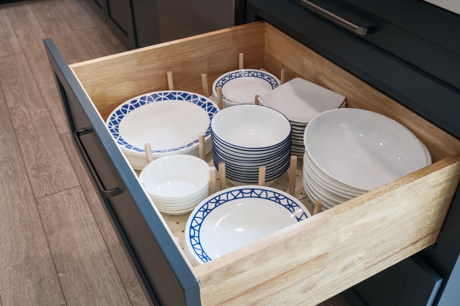 A wooden drawer filled with plates and bowls.