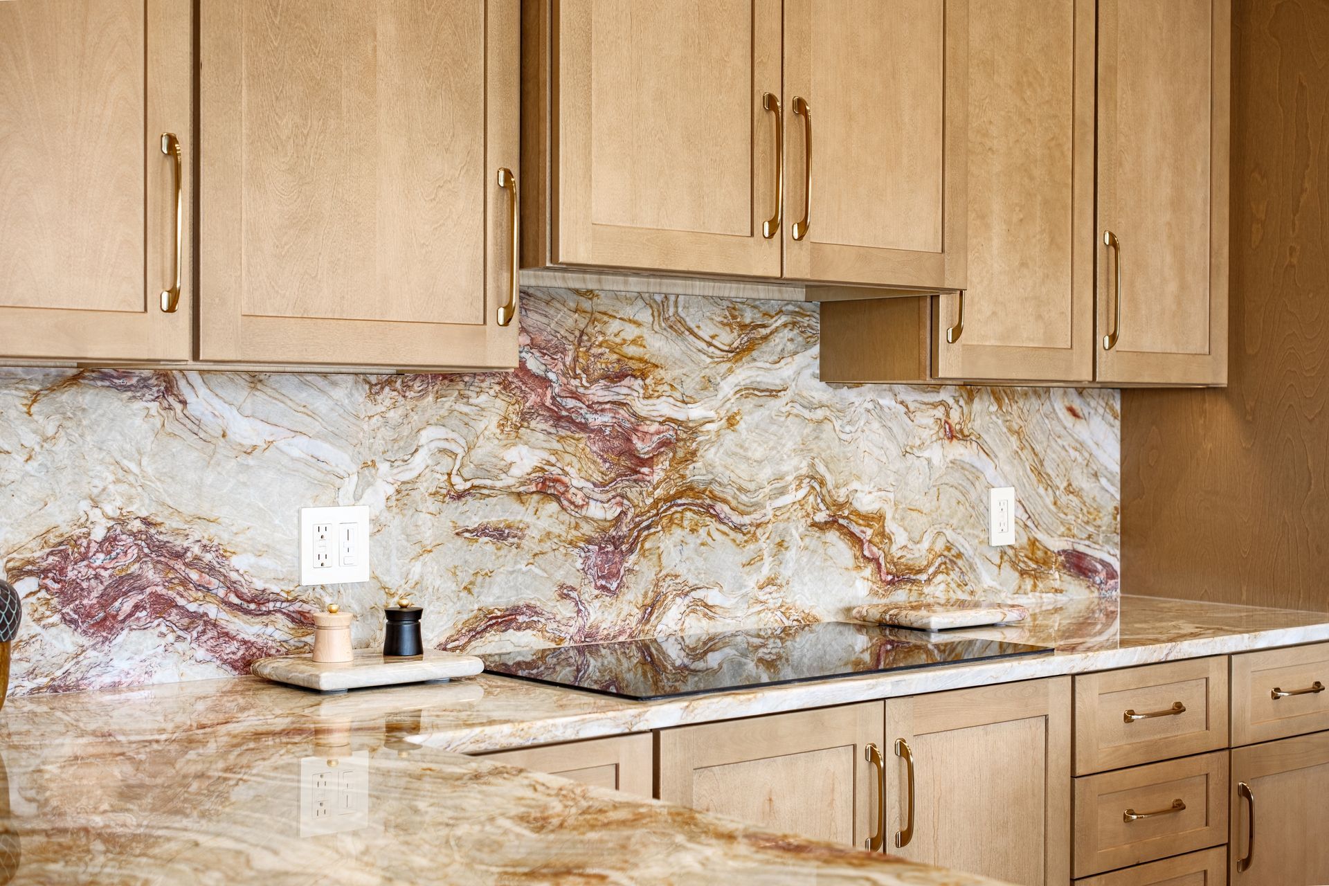 Light wood kitchen cabinets and countertop with a colorful, patterned backsplash.