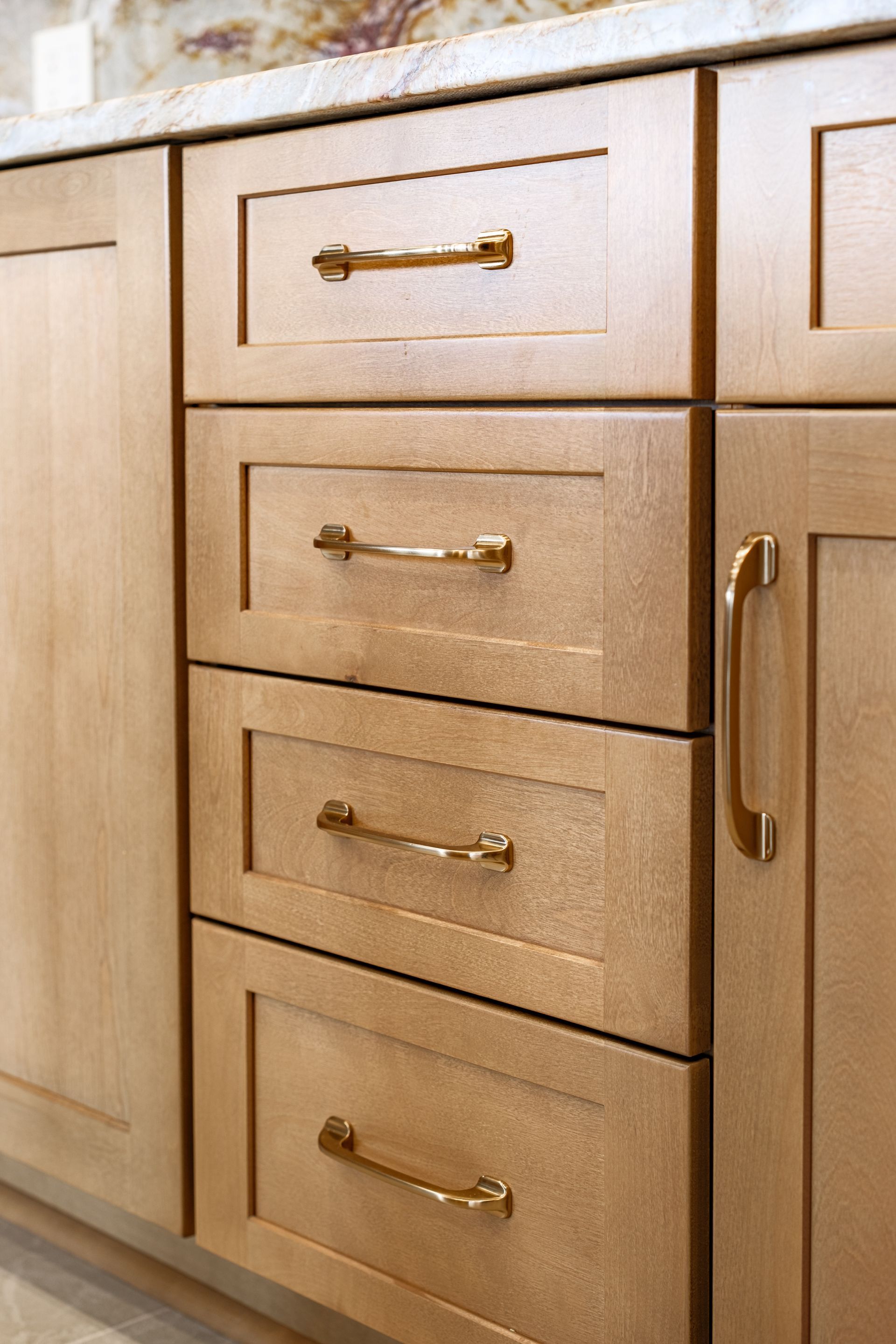 Light brown kitchen drawers with gold hardware.