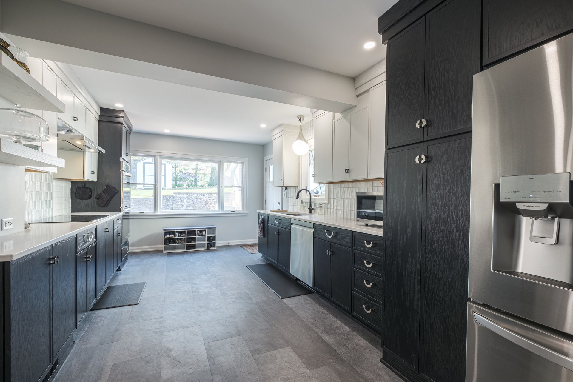 Modern kitchen with dark cabinets, stainless steel appliances, and gray flooring.