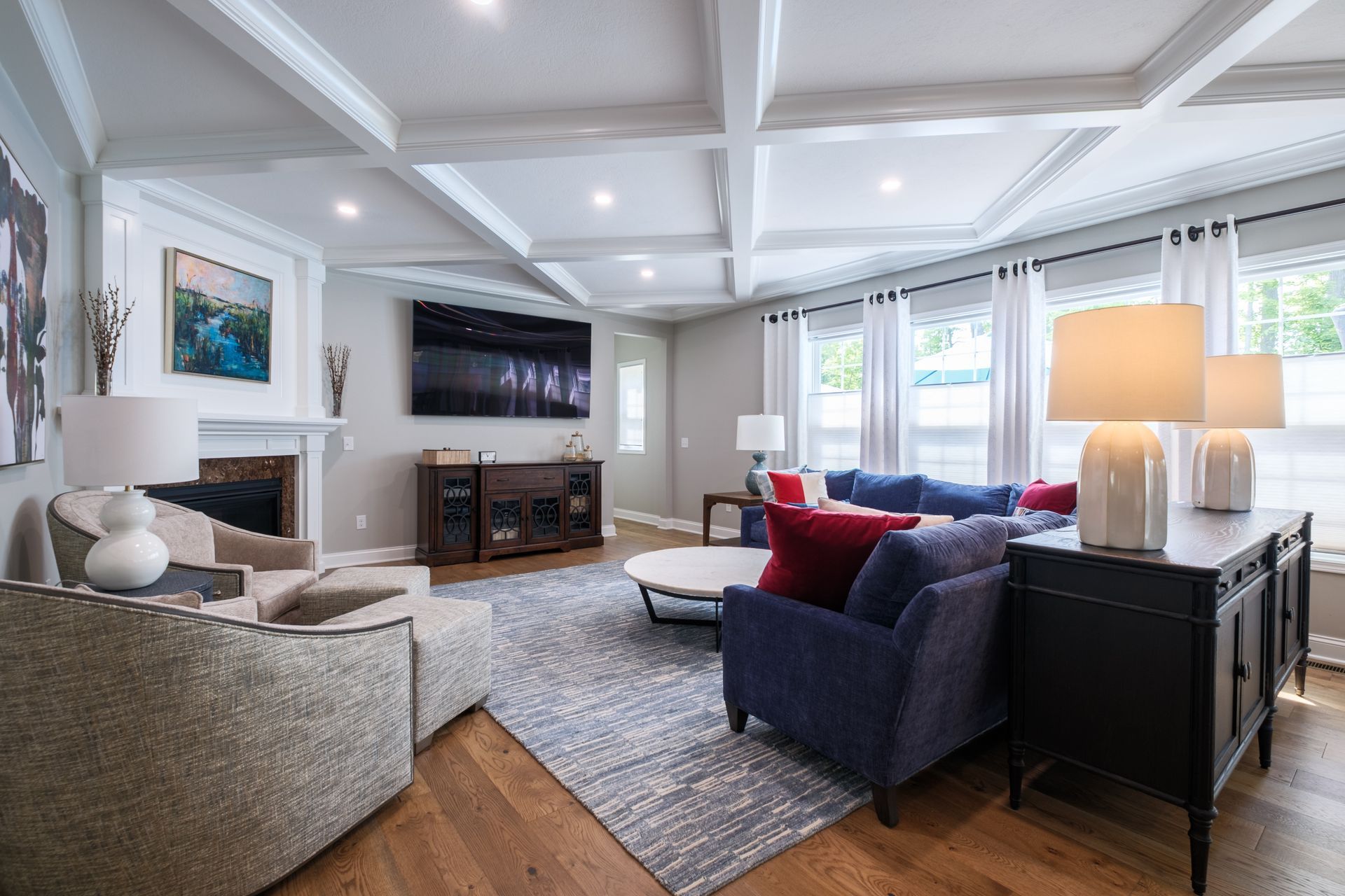 Living room with coffered ceiling, fireplace, TV, and blue and red furniture.