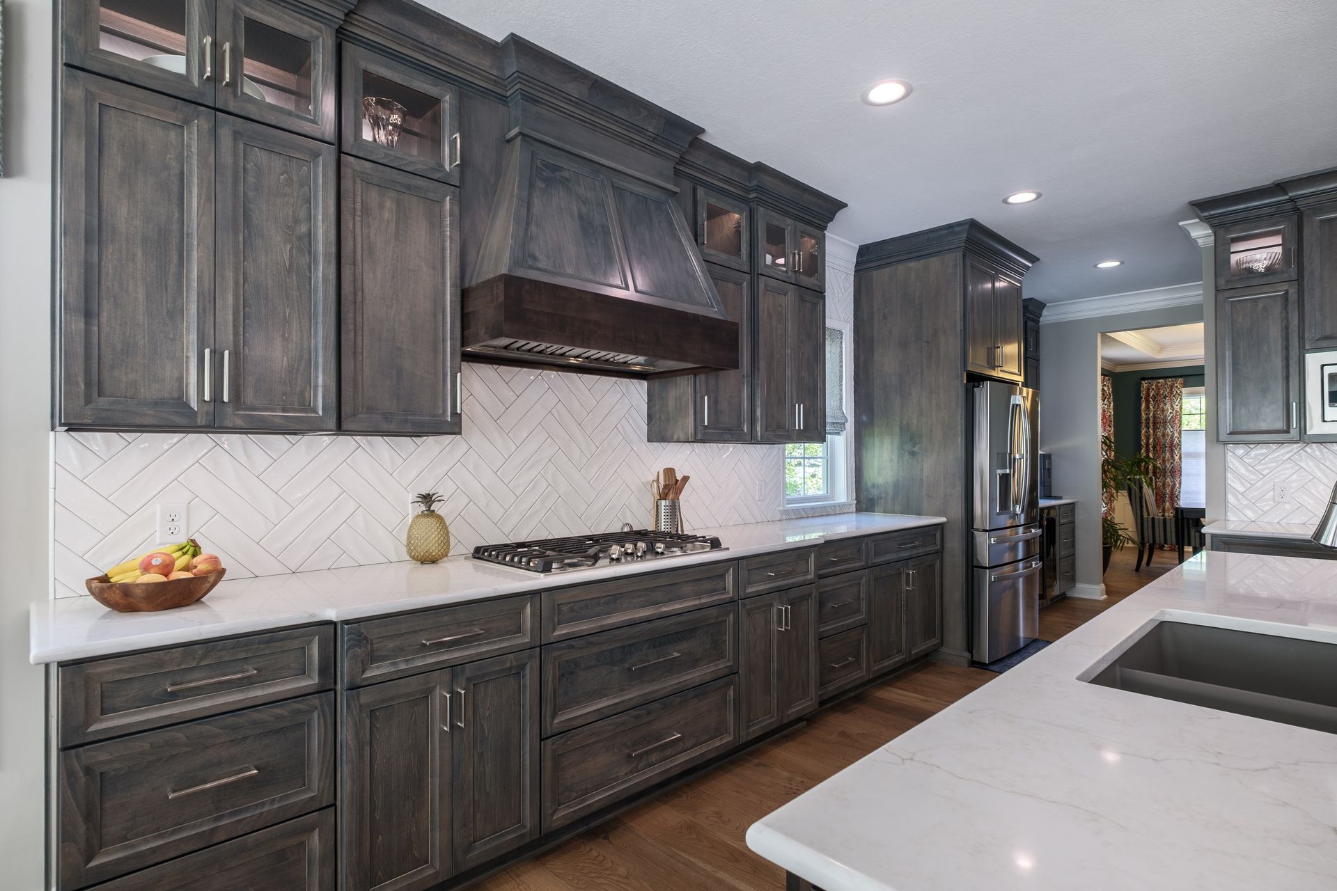 Gray kitchen with white countertops and herringbone backsplash.