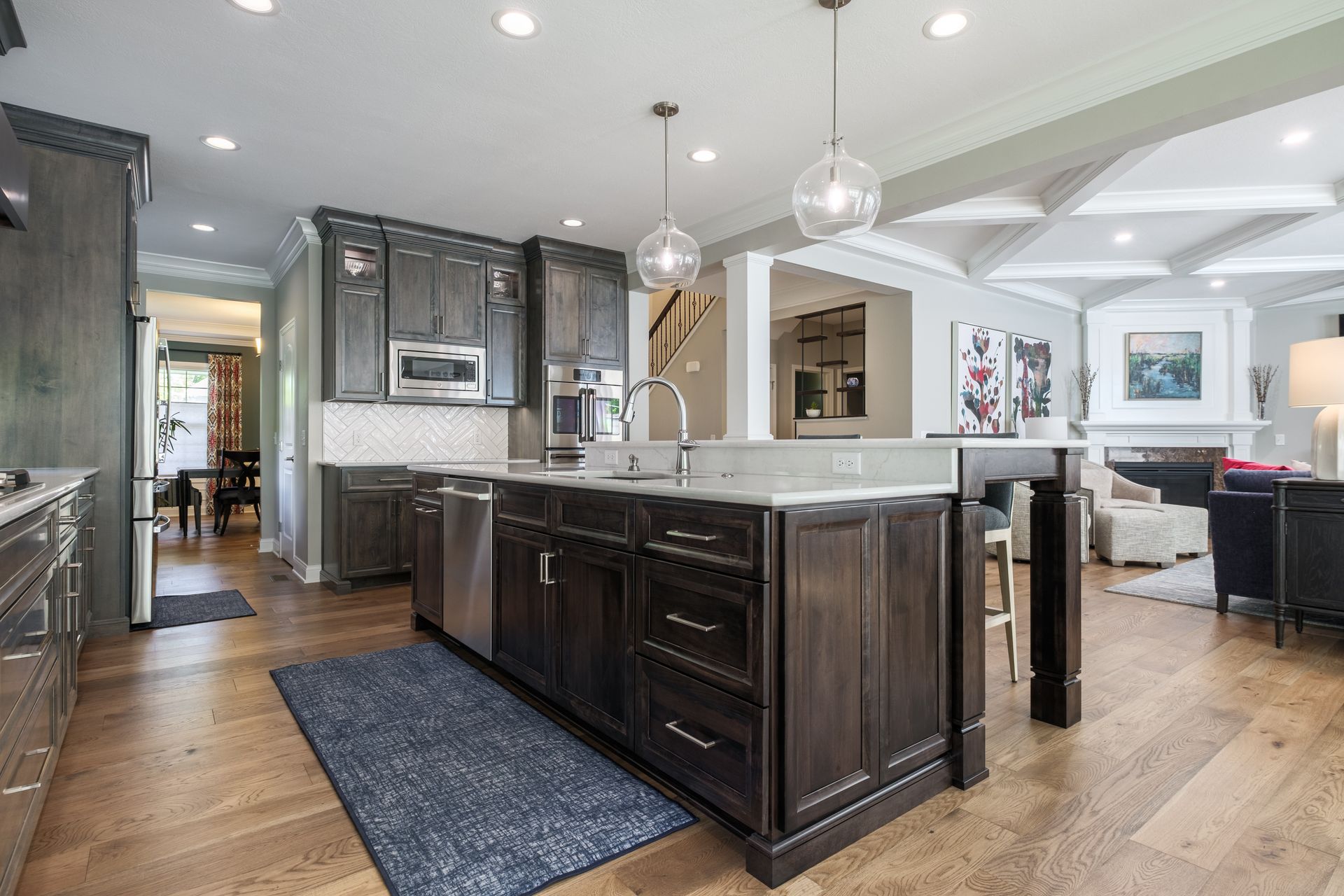 Modern kitchen with dark wood cabinets, island, and blue rug.
