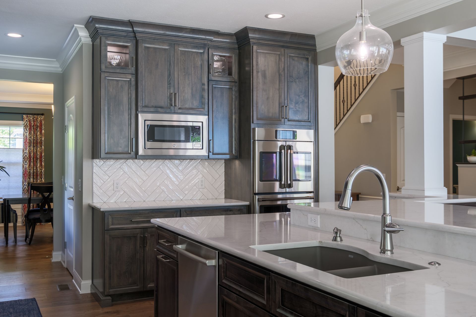 Kitchen with gray cabinets, white countertops, stainless steel appliances, and a hanging light.