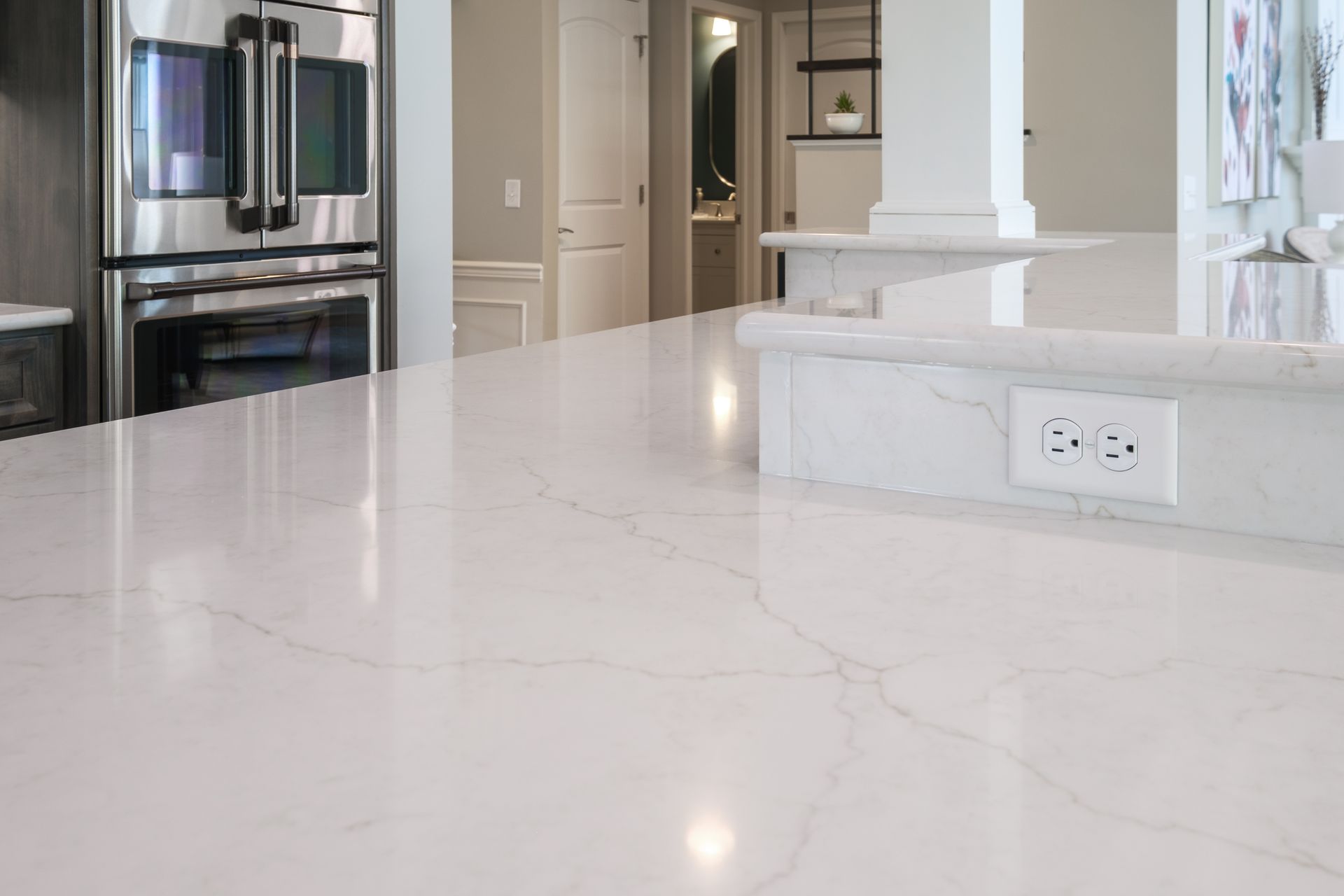 Close-up of a white marble countertop with a built-in outlet in a kitchen.