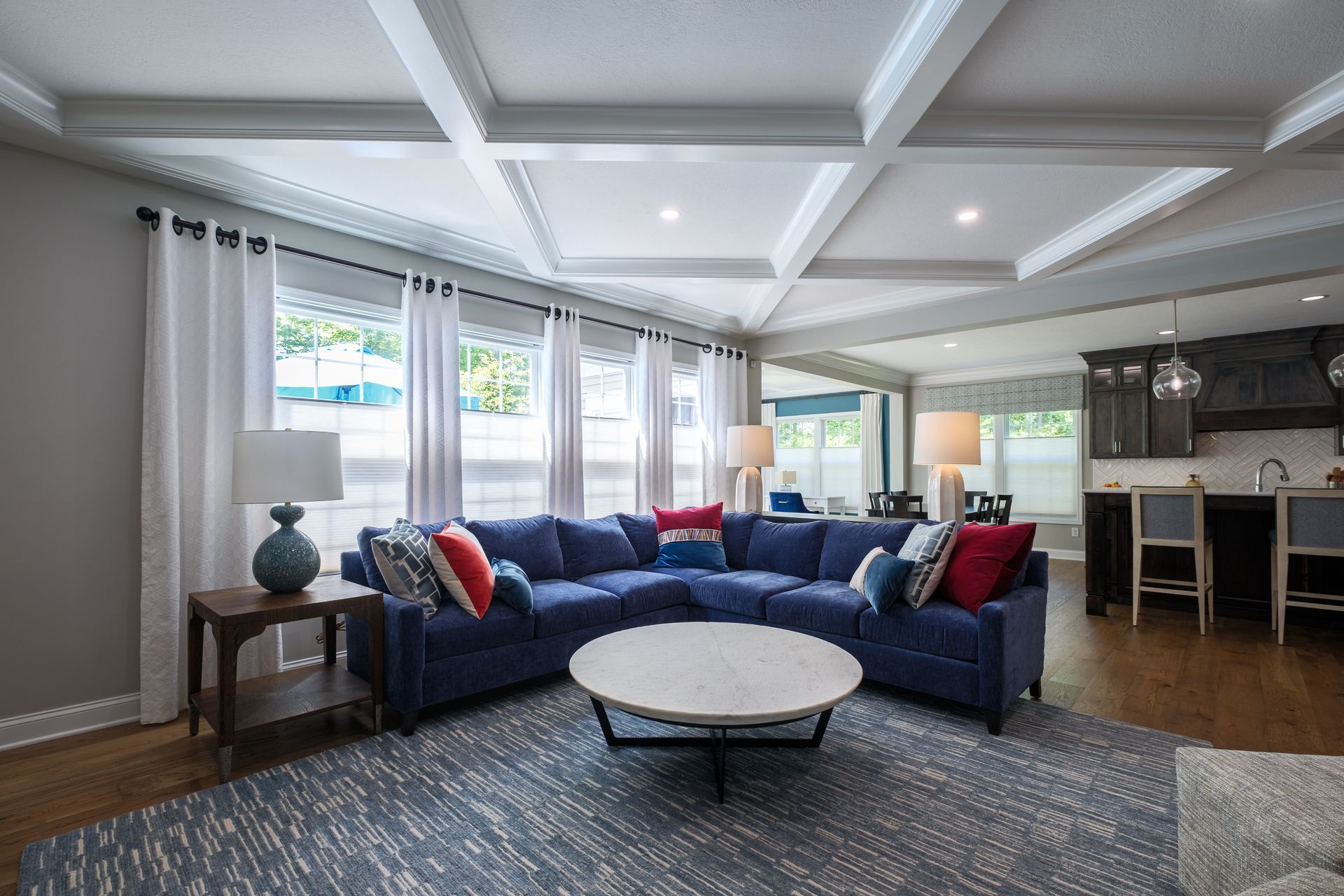 Living room with blue sectional sofa, round coffee table, and large windows.