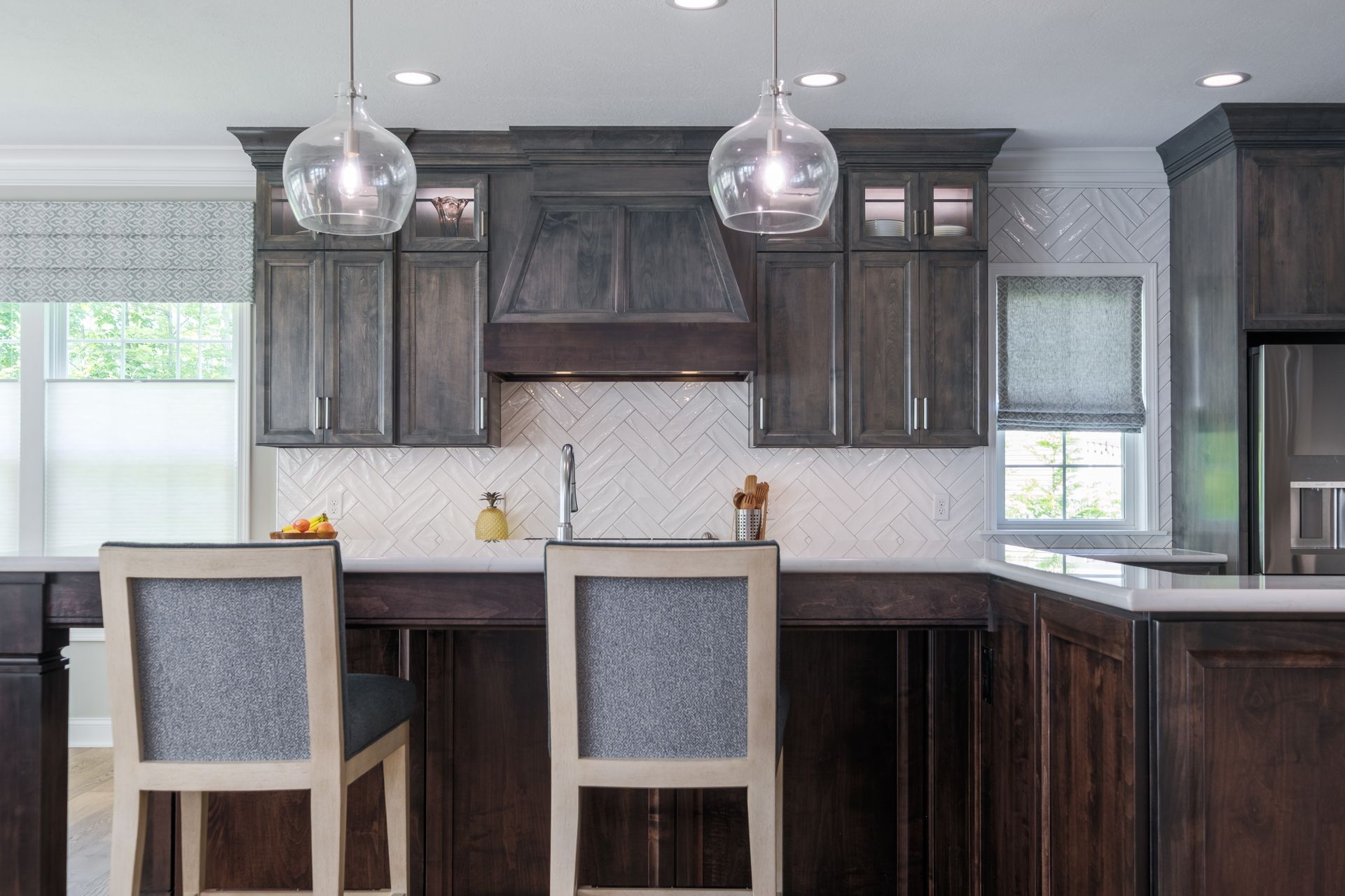 Kitchen with dark wood cabinets, white backsplash, and two barstools.