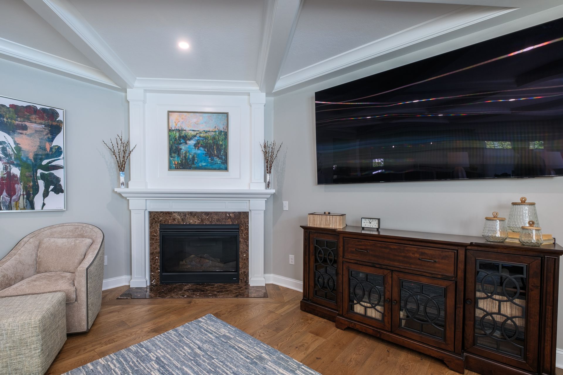 Living room with fireplace, TV, and wooden cabinet; light gray walls, wood floors.