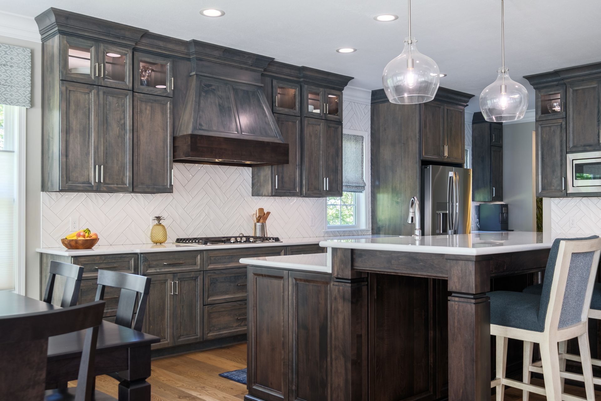 Dark wood kitchen with island, white countertops, and glass pendant lights.