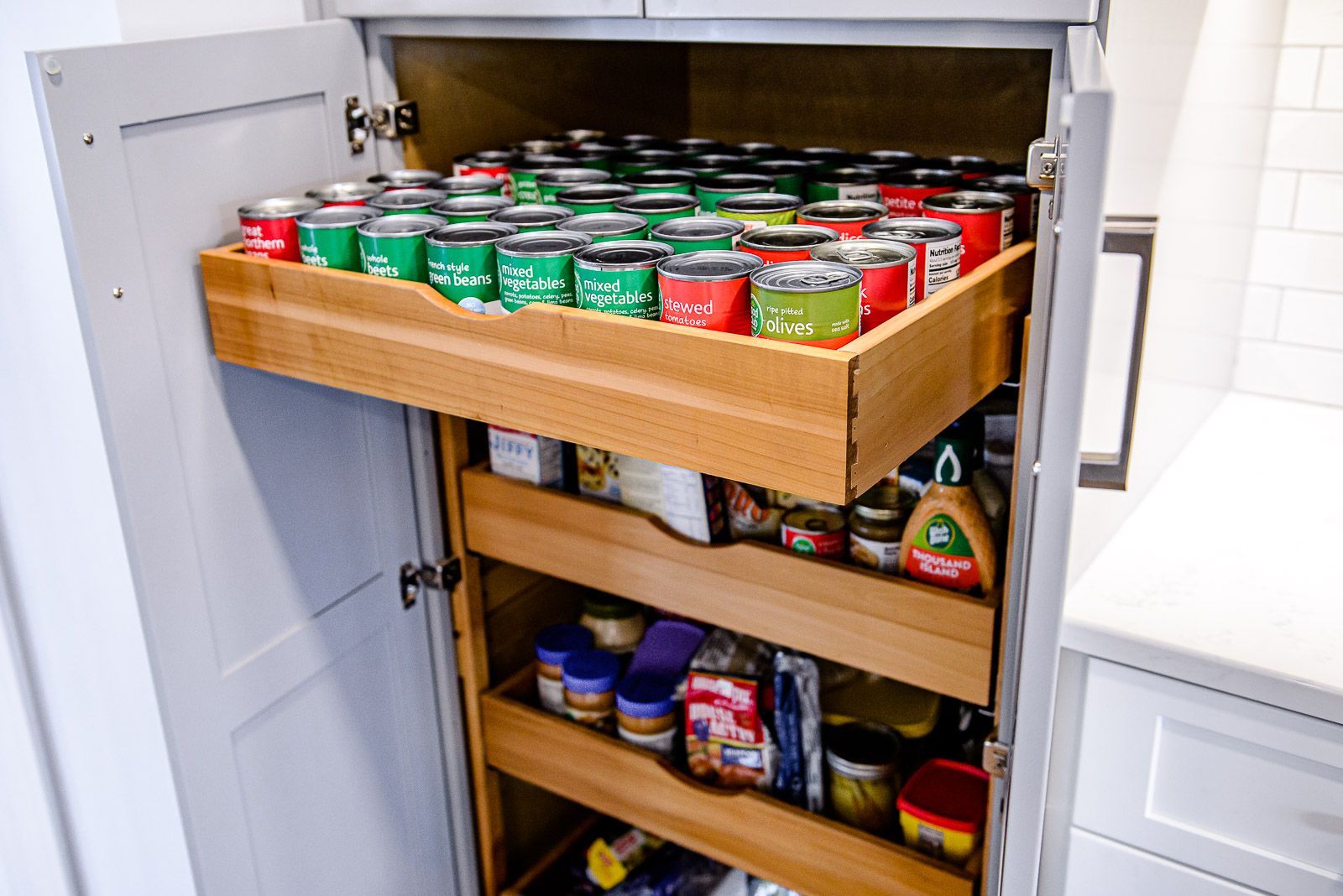 A kitchen pantry with a pull out tray filled with canned food.