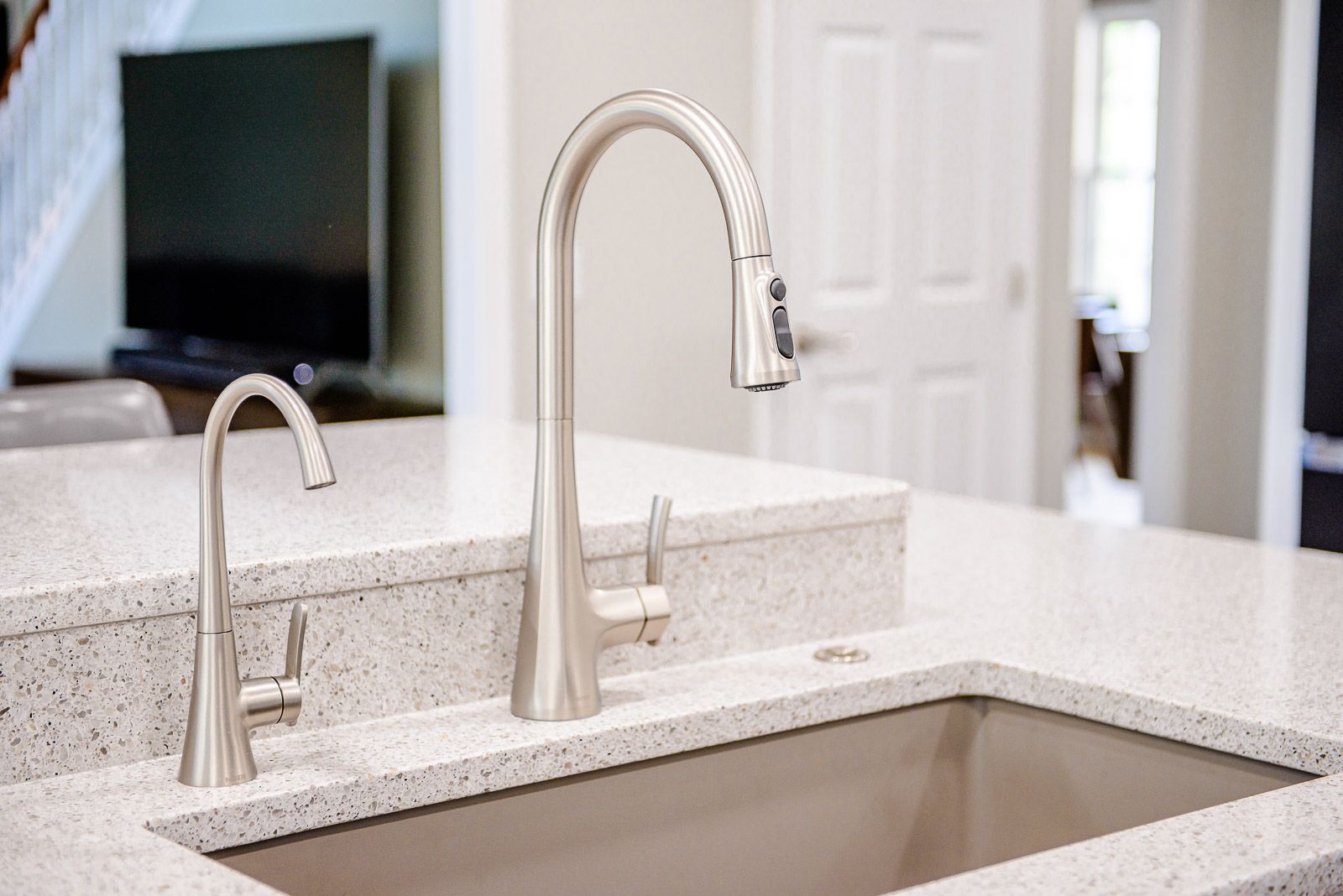 Kitchen sink with tall faucet, filtered water tap, and granite countertop.
