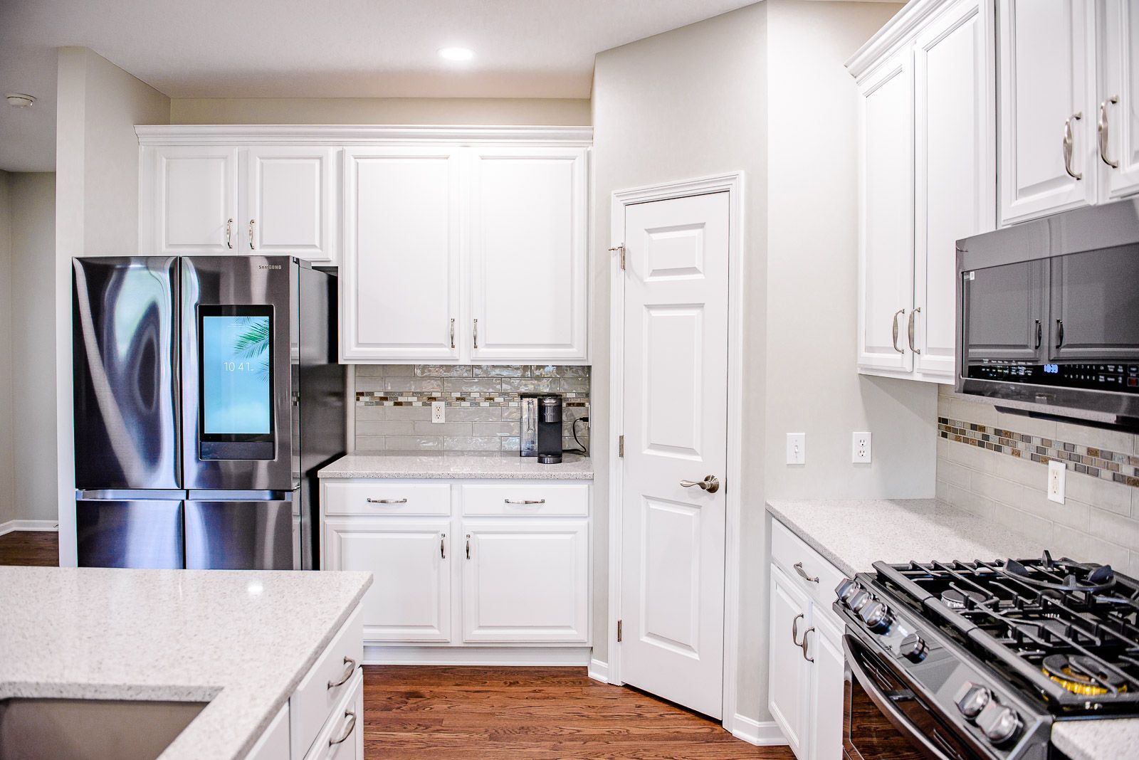 White kitchen with stainless steel appliances, cabinets, and light countertops.