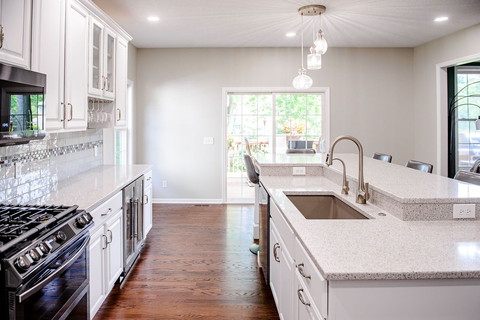 White kitchen with quartz countertops, dark stove, and sliding door to deck.