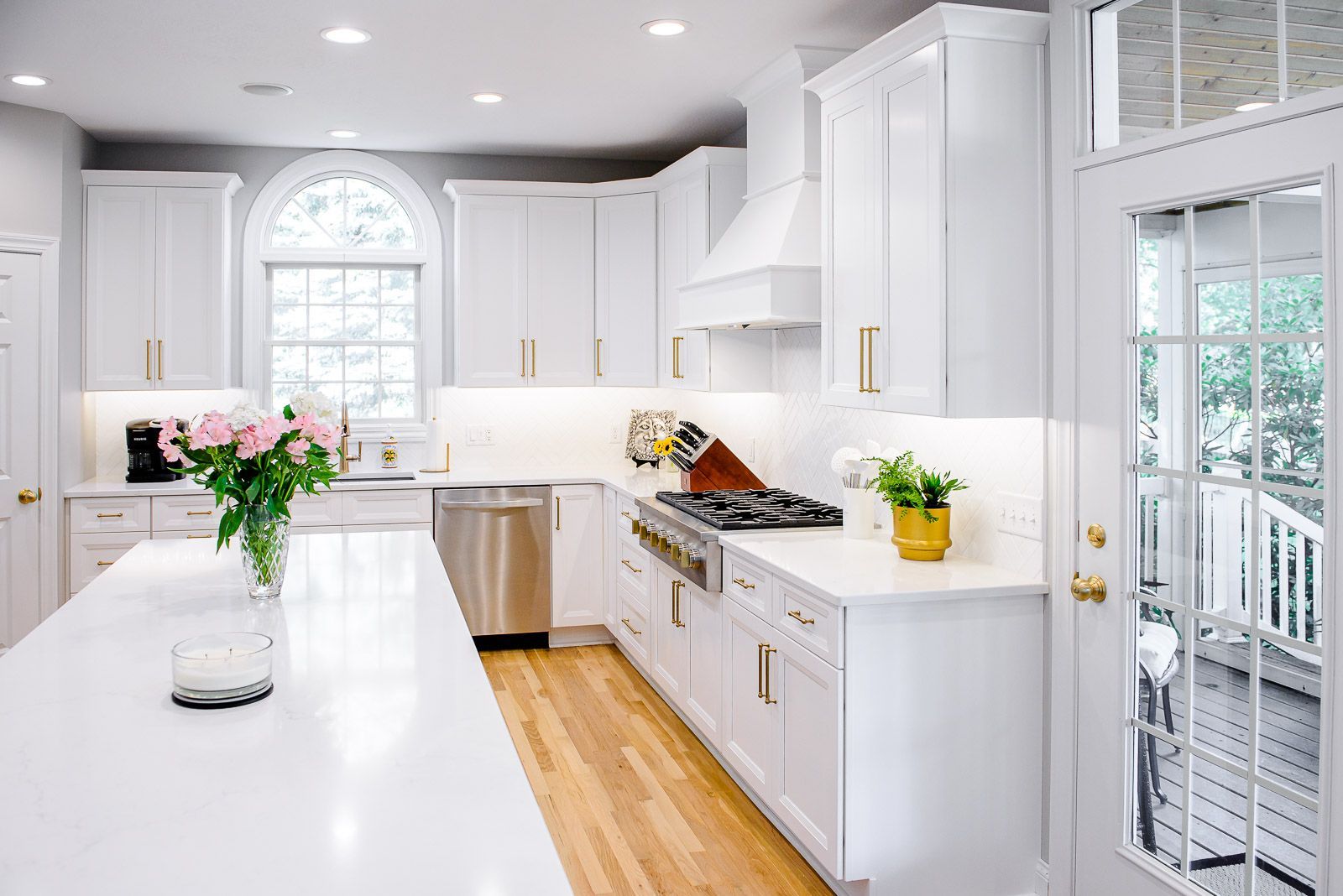 A kitchen with white cabinets , stainless steel appliances , and a large island.