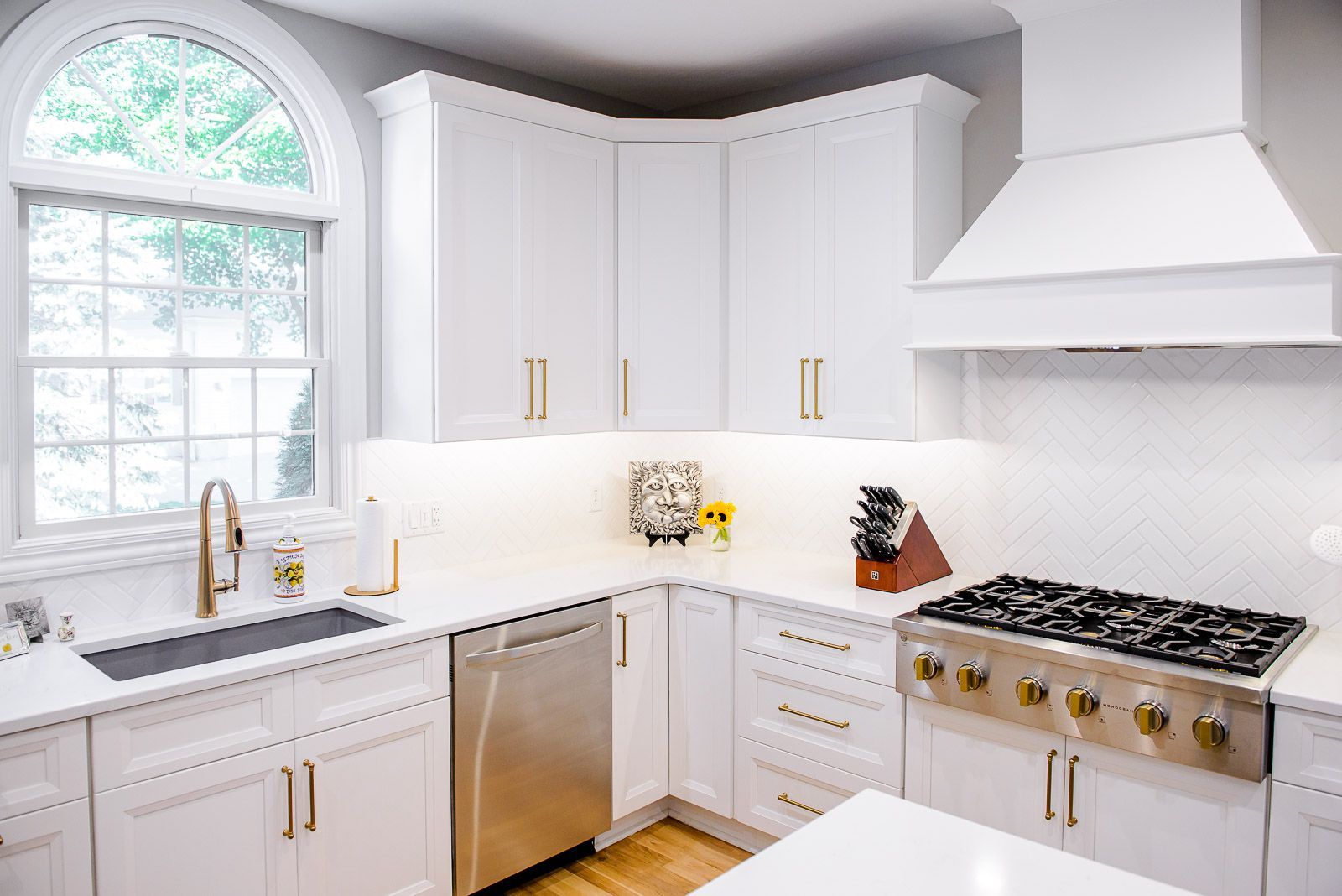A kitchen with white cabinets , stainless steel appliances , a stove and a sink.