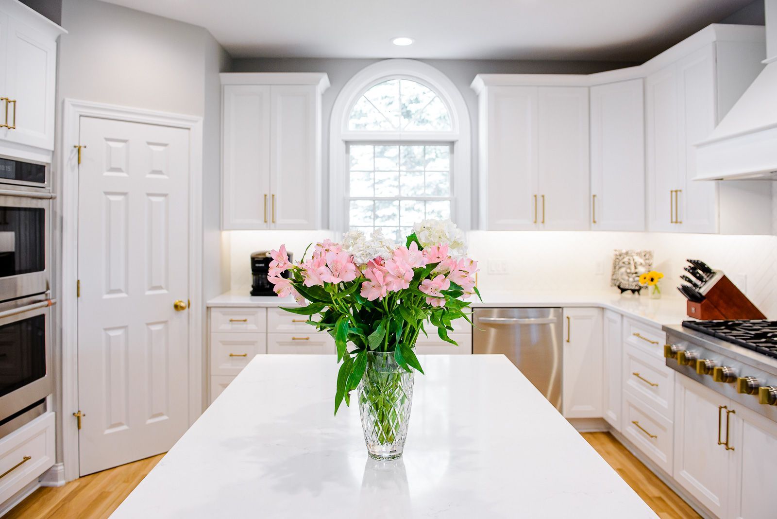 A kitchen with white cabinets and a vase of flowers on the counter.
