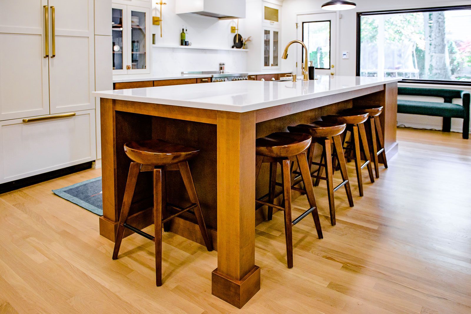 A kitchen with a large island and wooden stools.