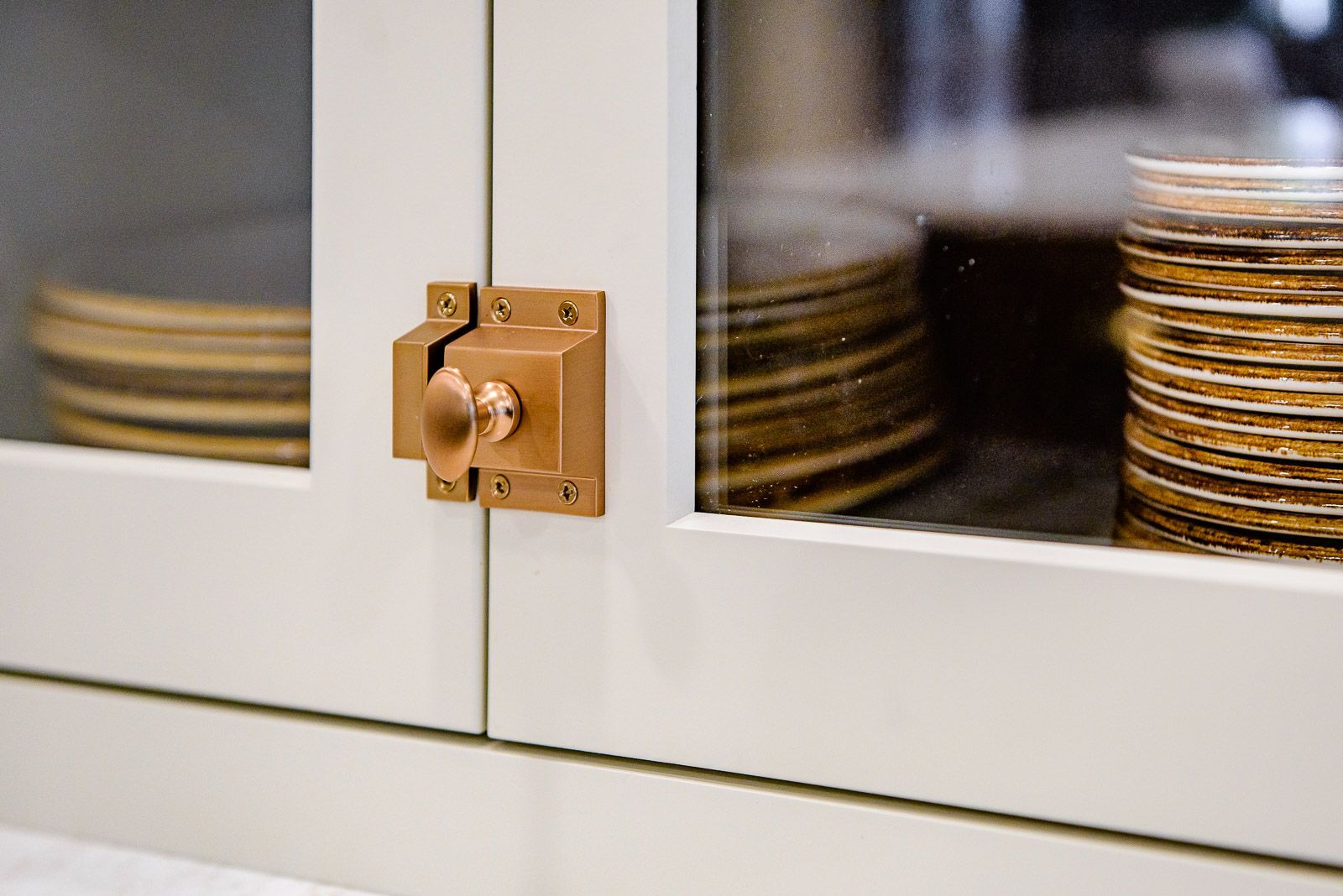 A stack of plates is sitting inside of a glass cabinet.