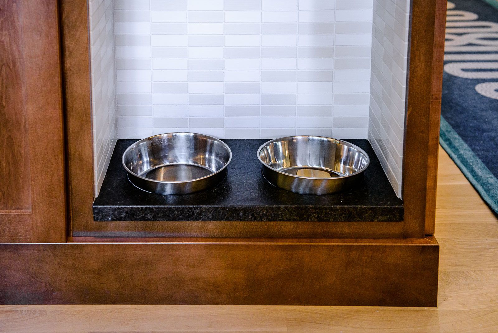 Two stainless steel bowls are sitting on top of a wooden shelf.