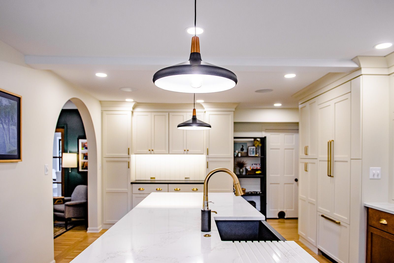A kitchen with white cabinets and a large island with a sink.