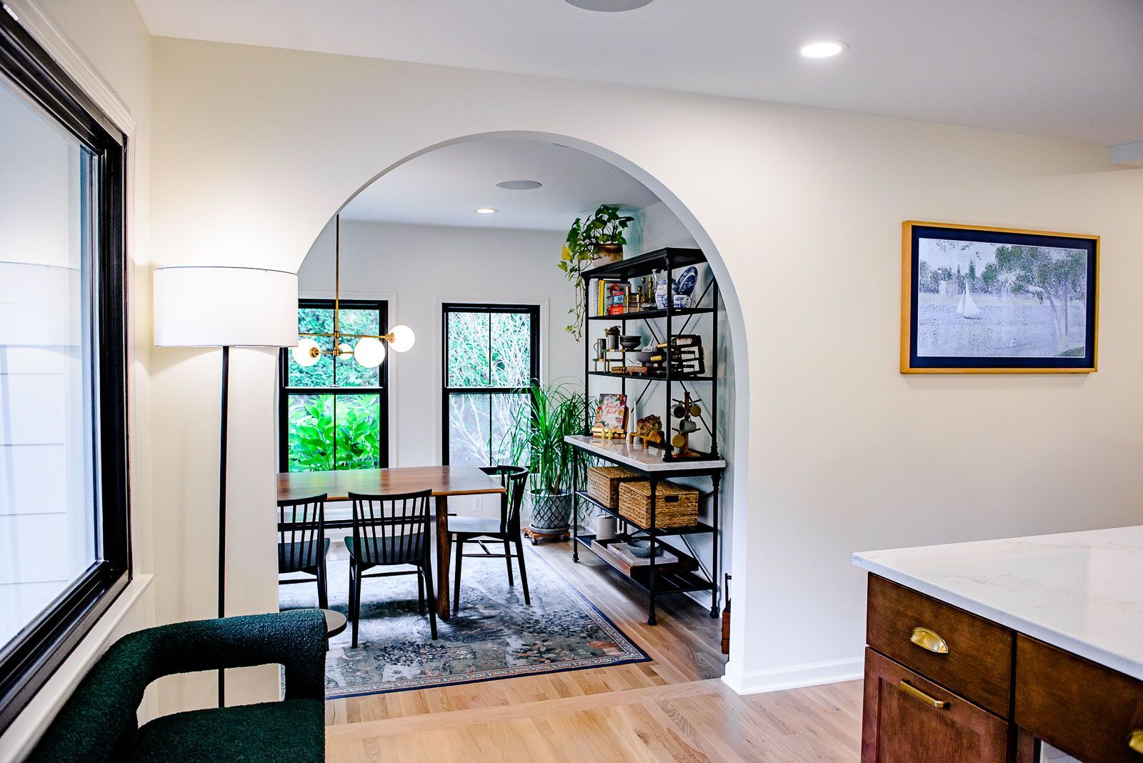 A living room with a dining room table and chairs and an archway leading to the dining room.