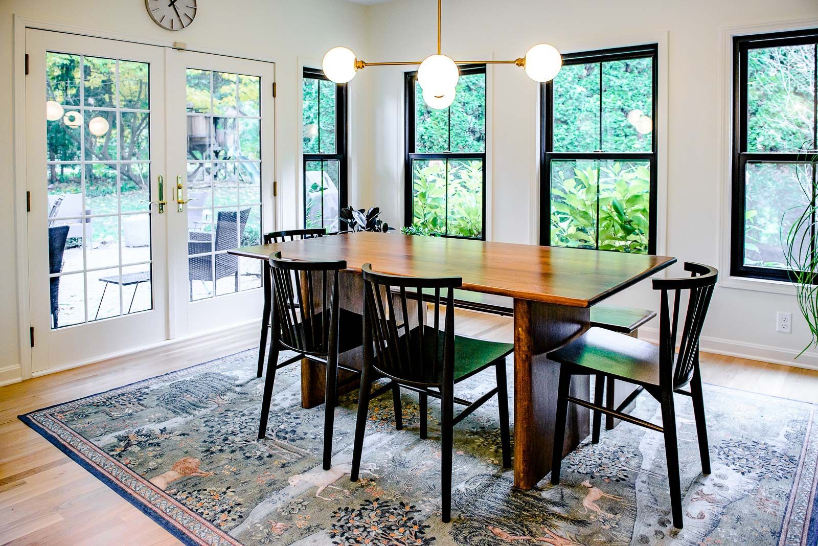 A dining room with a table and chairs and a rug.